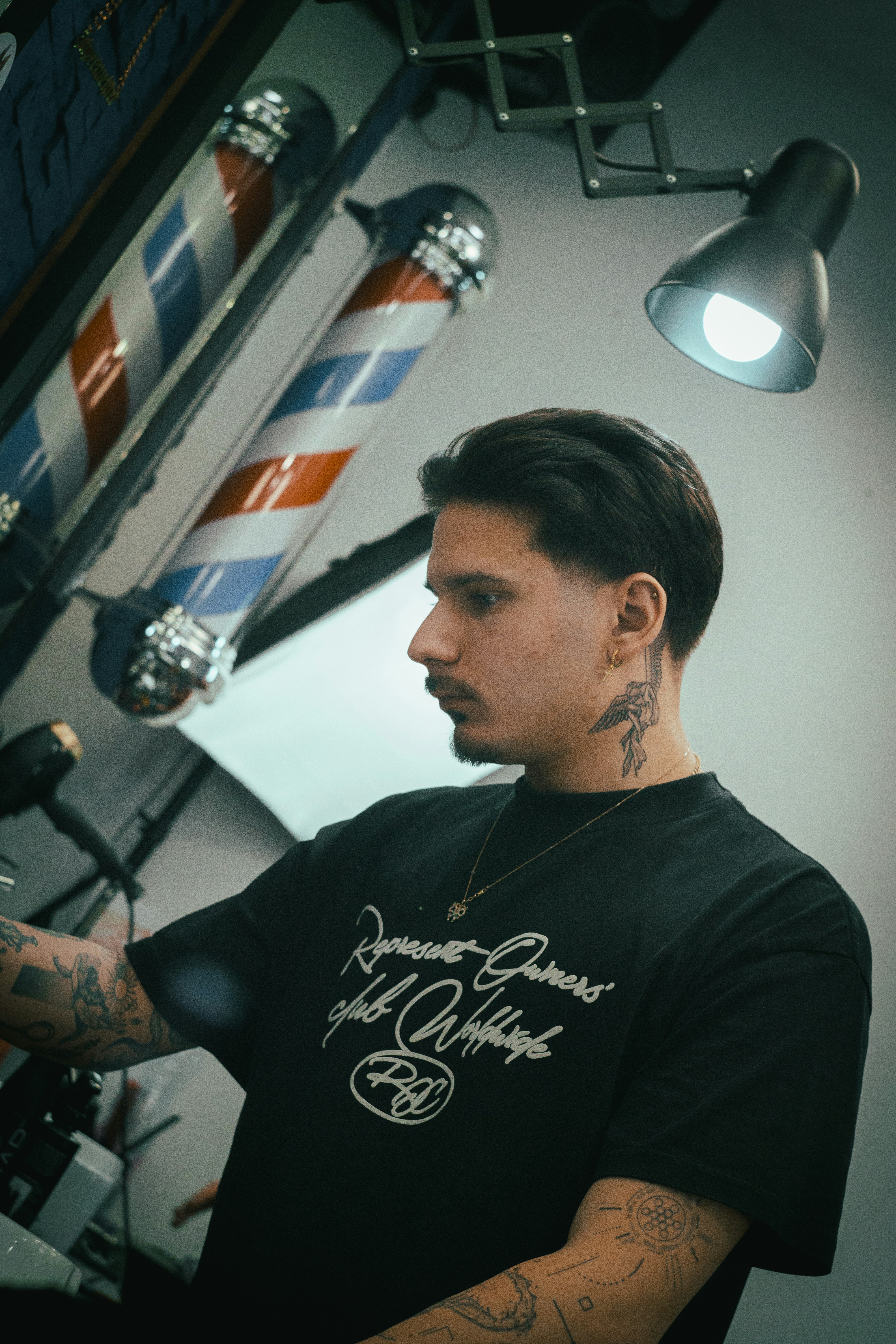 Barber standing near barber poles in a shop.