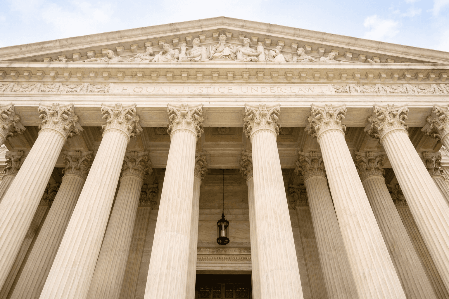 Low-angle view of a neoclassical courthouse with tall columns and a sculpted pediment.