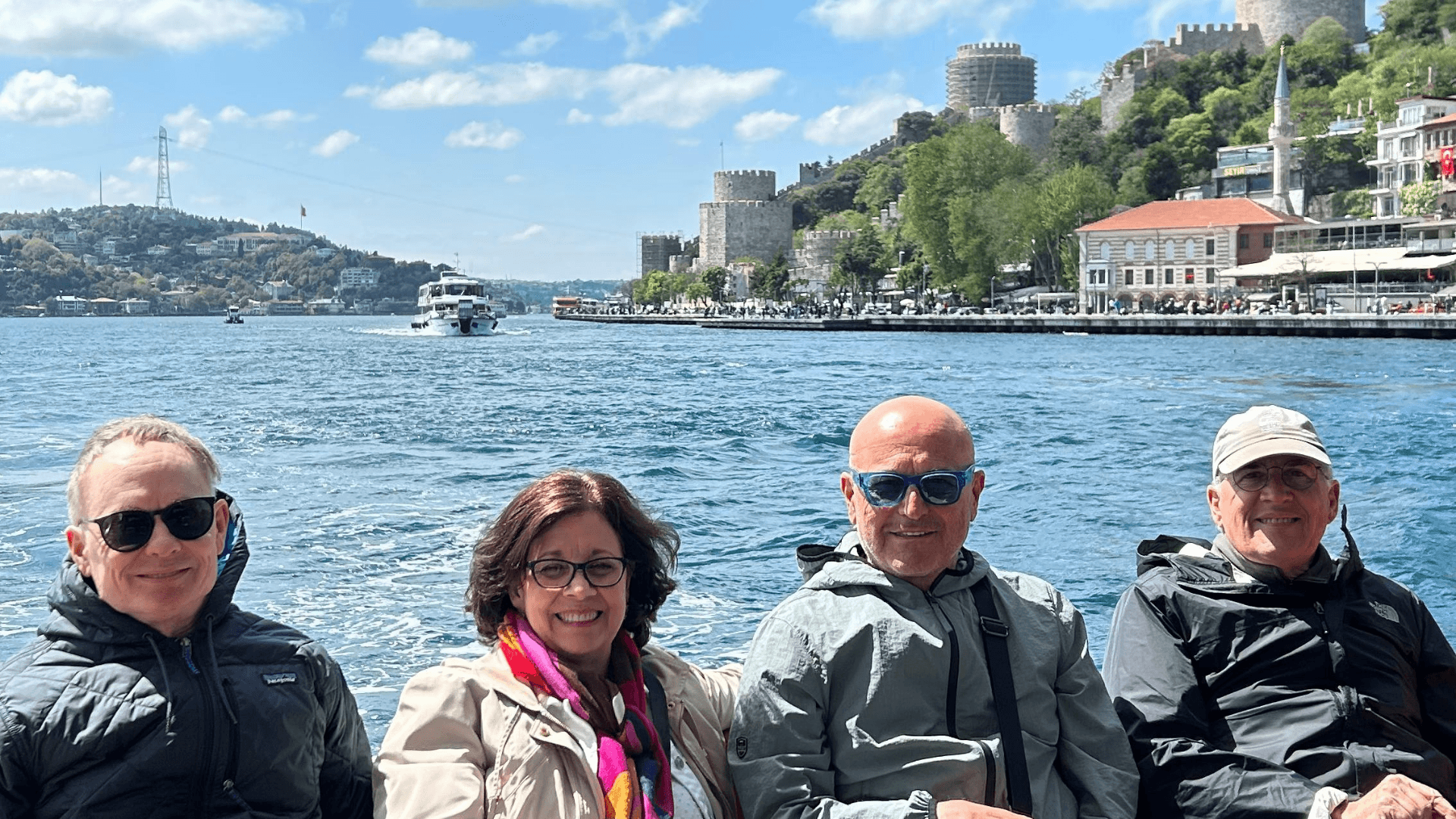 Travelers enjoying a Bosphorus boat tour in Istanbul with waterfront views, historic city walls, and scenic coastline on a sunny day
