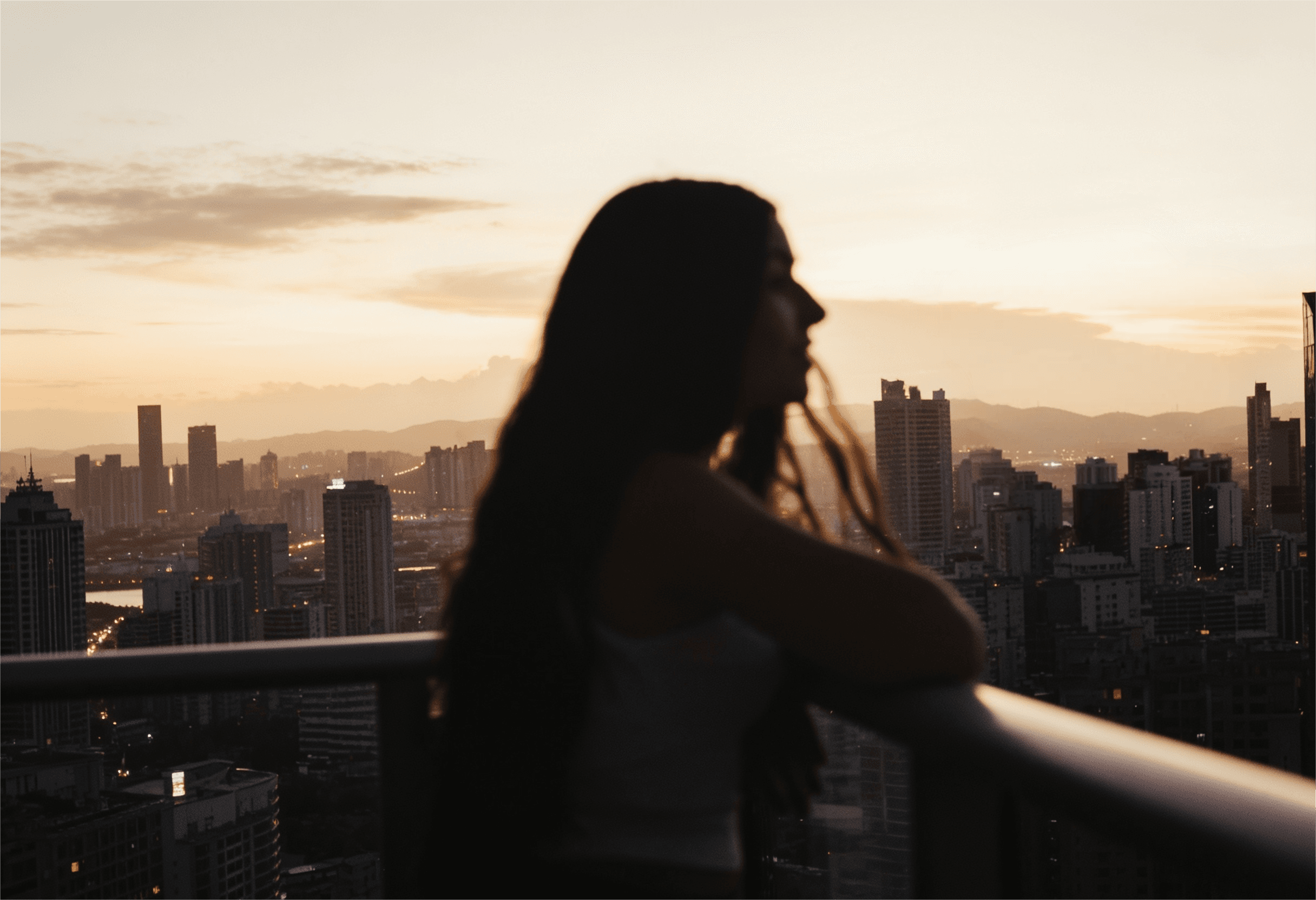 Frauensilhouette vor Stadtpanorama bei Sonnenuntergang – Dreambooster Nutzerin