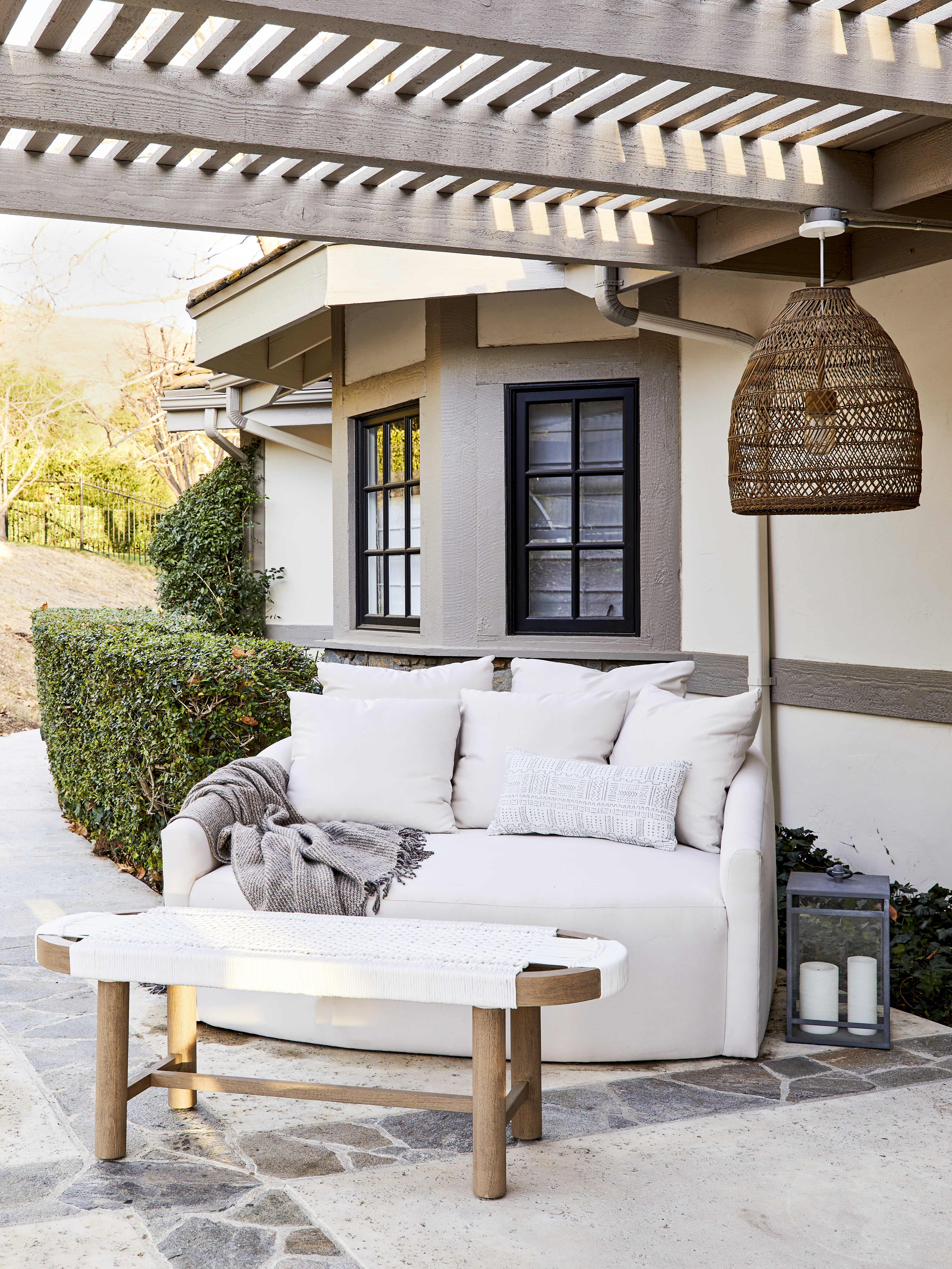 This luxurious interior features a limestone fireplace, timber accents, woven wooden chairs, and a natural wood coffee table, all unified by an earthy tonal palette