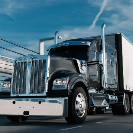 Black semi-truck driving on bridge representing semi truck insurance cost.