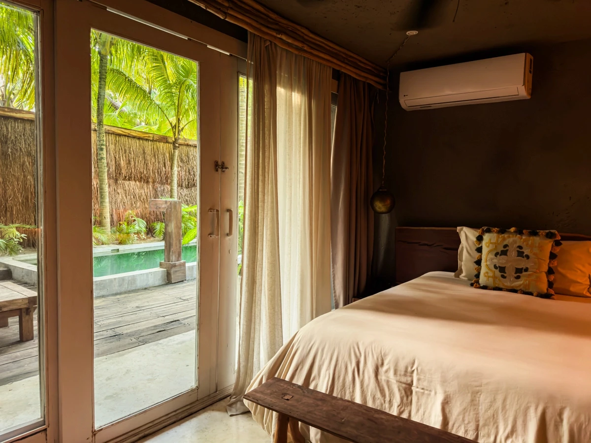Two Bedroom Villa with Pool at Nômade Tulum featuring 2 spacious beds with pillows, hanging lamps, and dressers, with jungle view.