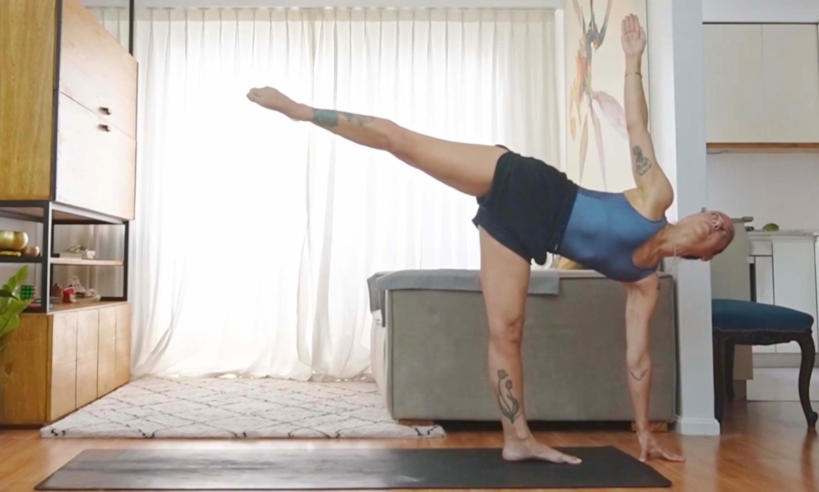 Flavia Siutti practicando una postura de equilibrio lateral sobre una esterilla de yoga.