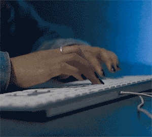 Plan rapproché des mains tapant sur un clavier pour saisir une référence Pop Culture dans PopCorn Garage lors d'une soirée d'entreprise.