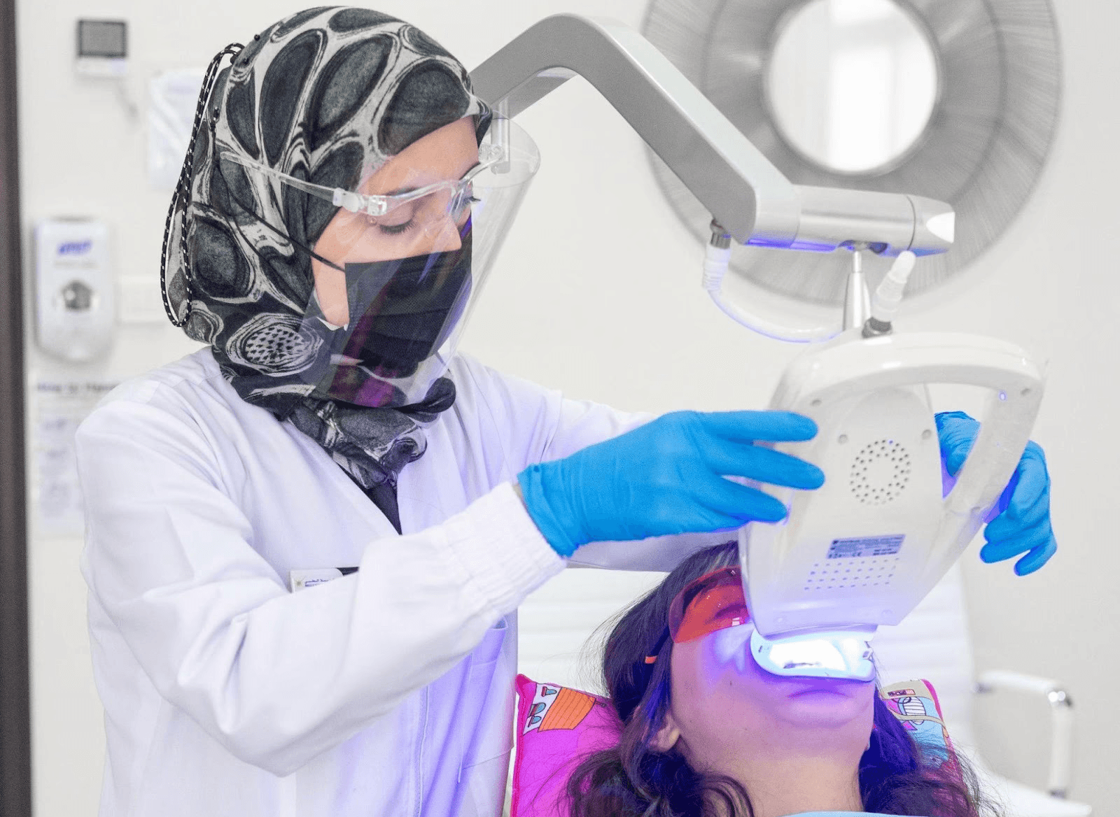 A cosmetic dentist at Bella Medical Center wearing a mask and scrubs while performing a Hollywood Smile treatment.