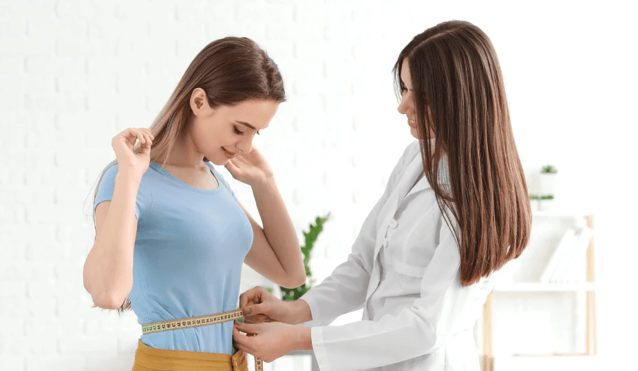 Clinic professional measuring a woman's waist."