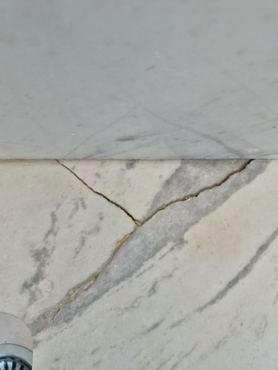 Cracked white Carrara marble vanity before repair in Dubai