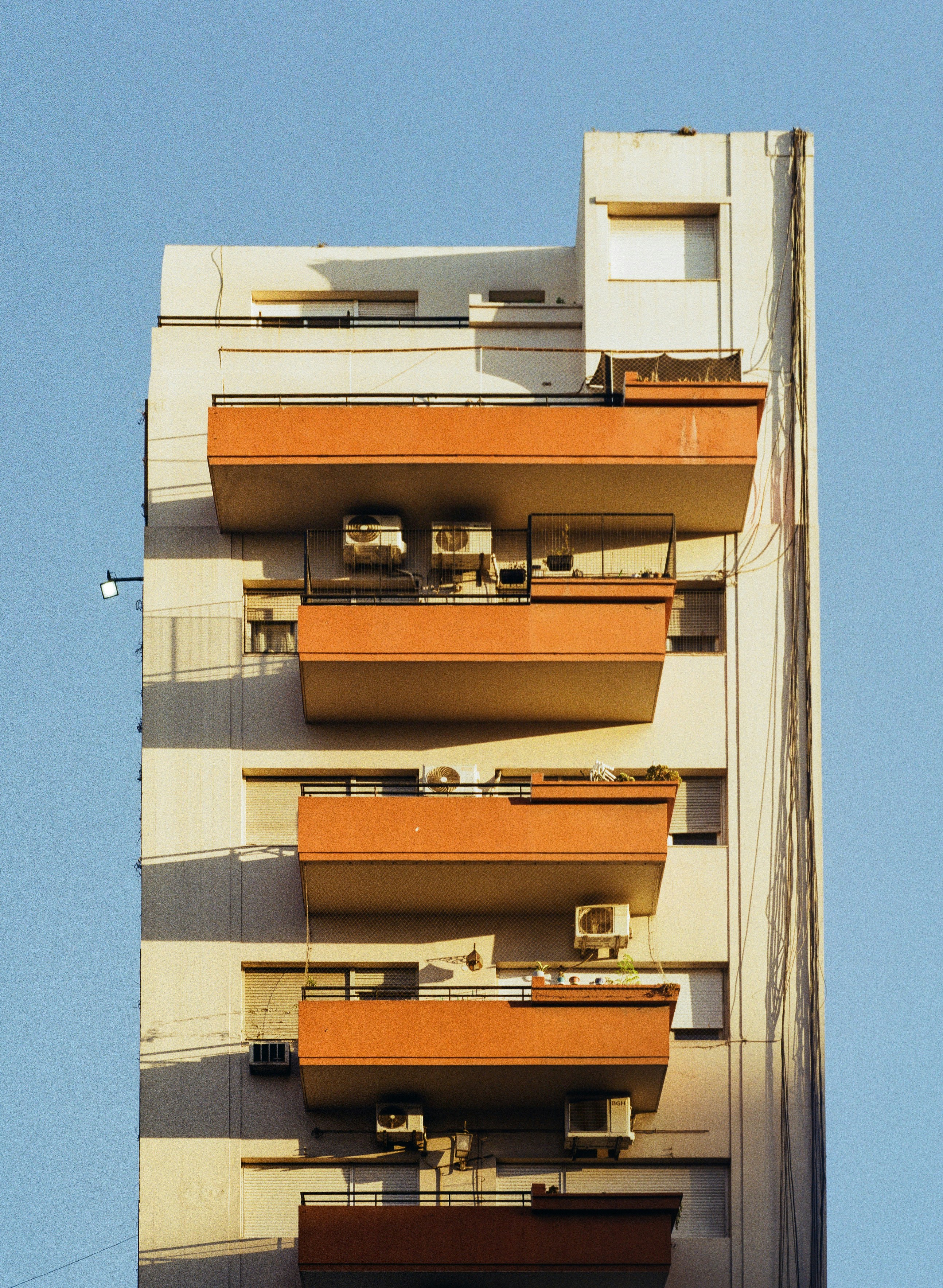 Modern apartment building with orange balconies and air conditioners.