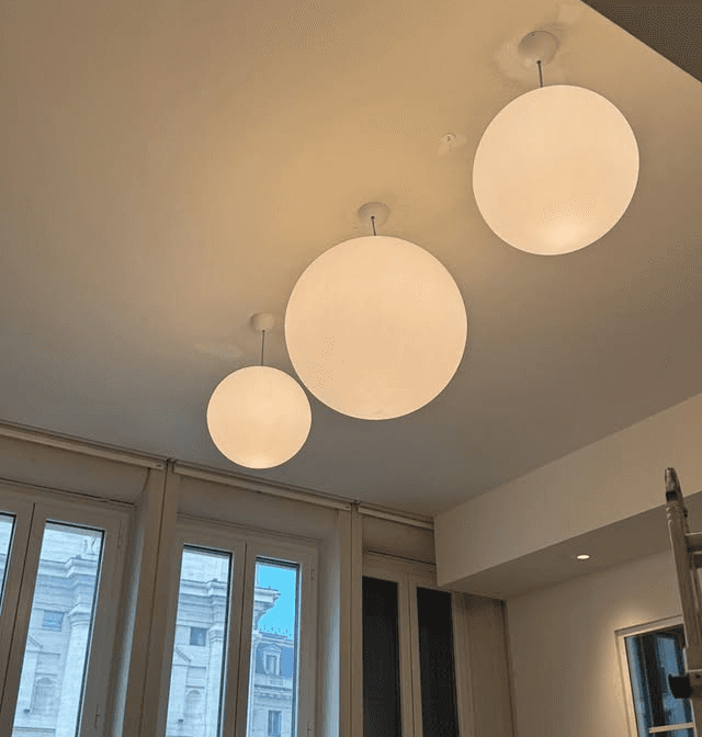 Modern indoor space with large glass doors, lush greenery, and a cozy seating area visible beyond.