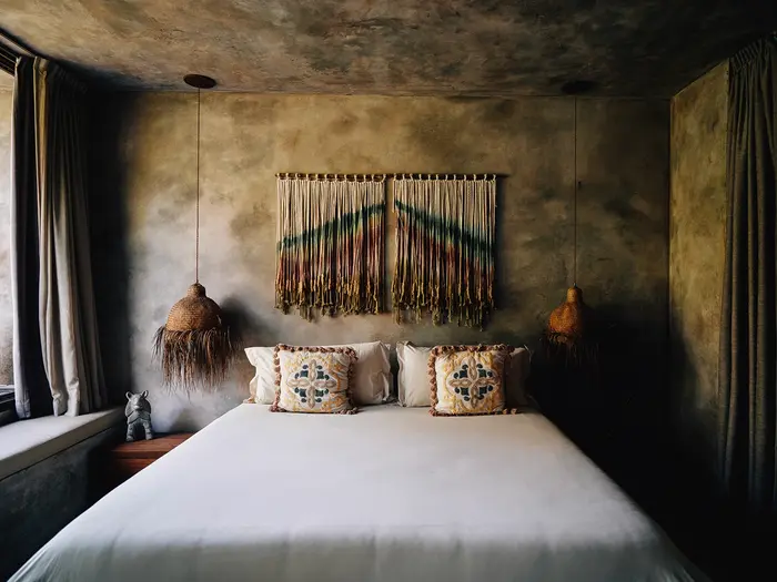 Premier Jungle Suite at Nômade Tulum featuring luxurious finishes and incredible design, comfortable bed with pillows and cushions, and 2 hanging lamps in harmony.