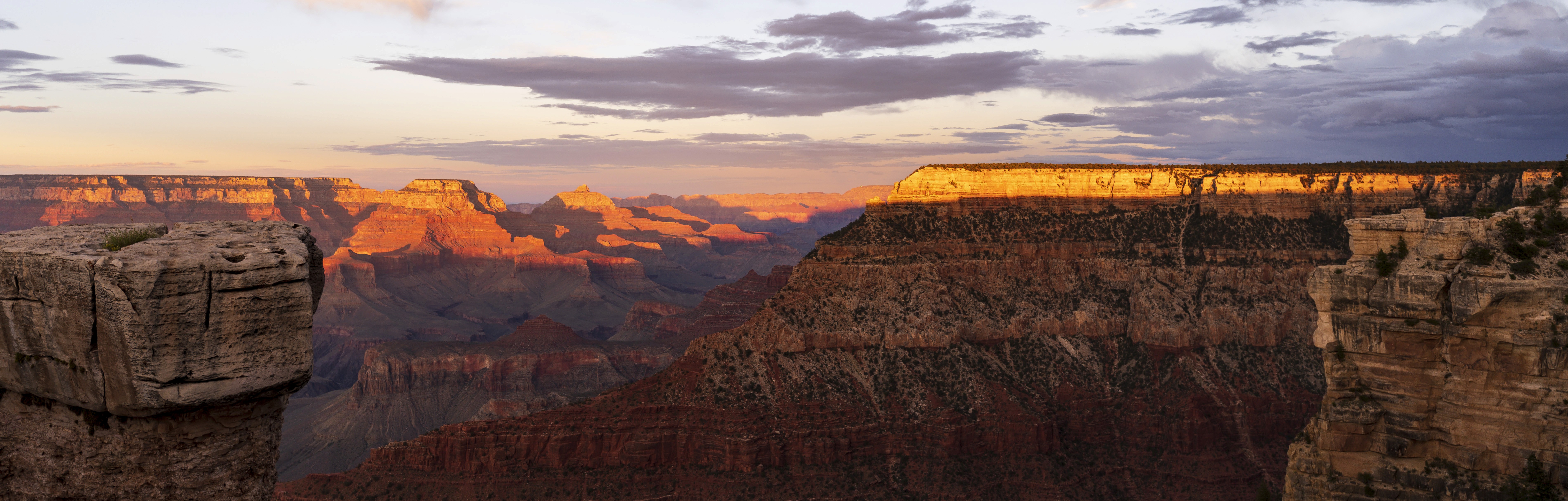 The Grand Canyon at sunset from the South Rim, layered red and grey buttes running to the horizon with the last light catching the far rim.