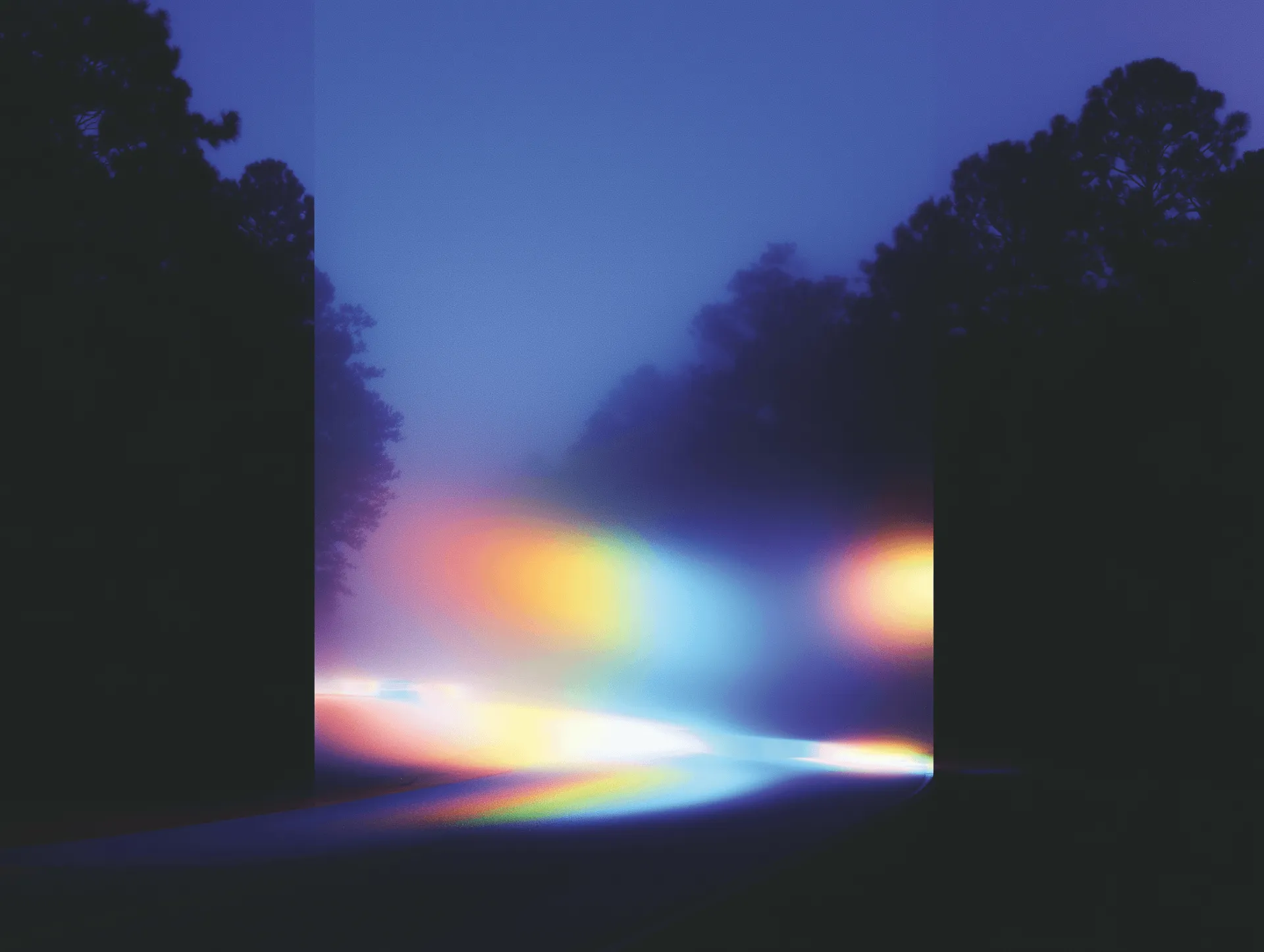 Abstract image of a rainbow light streak on a road at dusk