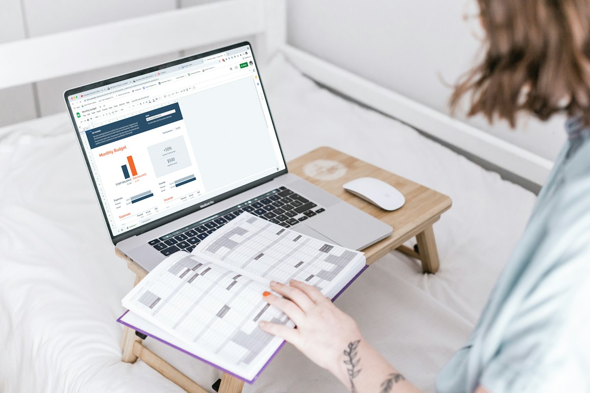 Woman working at a laptop beside an open paper planner