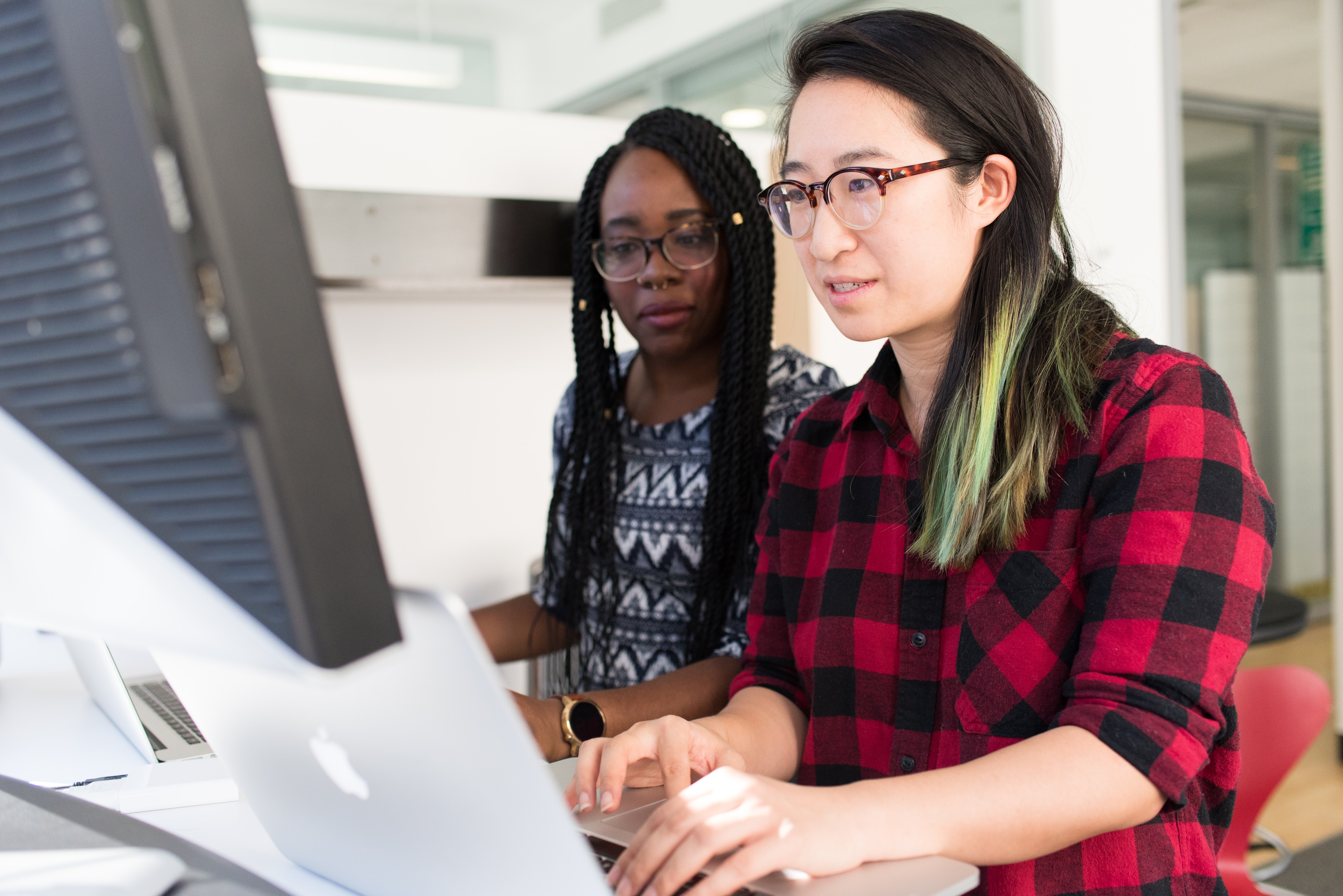 woman working on computer and showing coworker how to do sentiment analysis