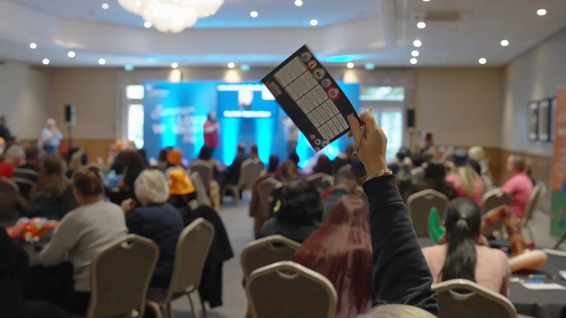 Audience member holding up a winning bingo card during an interactive Bupa Care session.