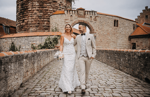 Ein Brautpaar auf einer historischen Steinbrücke, fotografiert von BKfotofilm – professionelle Hochzeitsfotografie und Hochzeitsfilme in Würzburg.