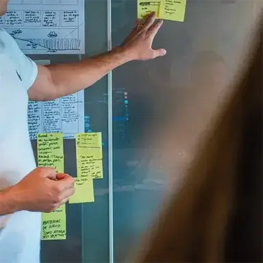 Man pointing a Post-it note at a whiteboard during a design sprint.