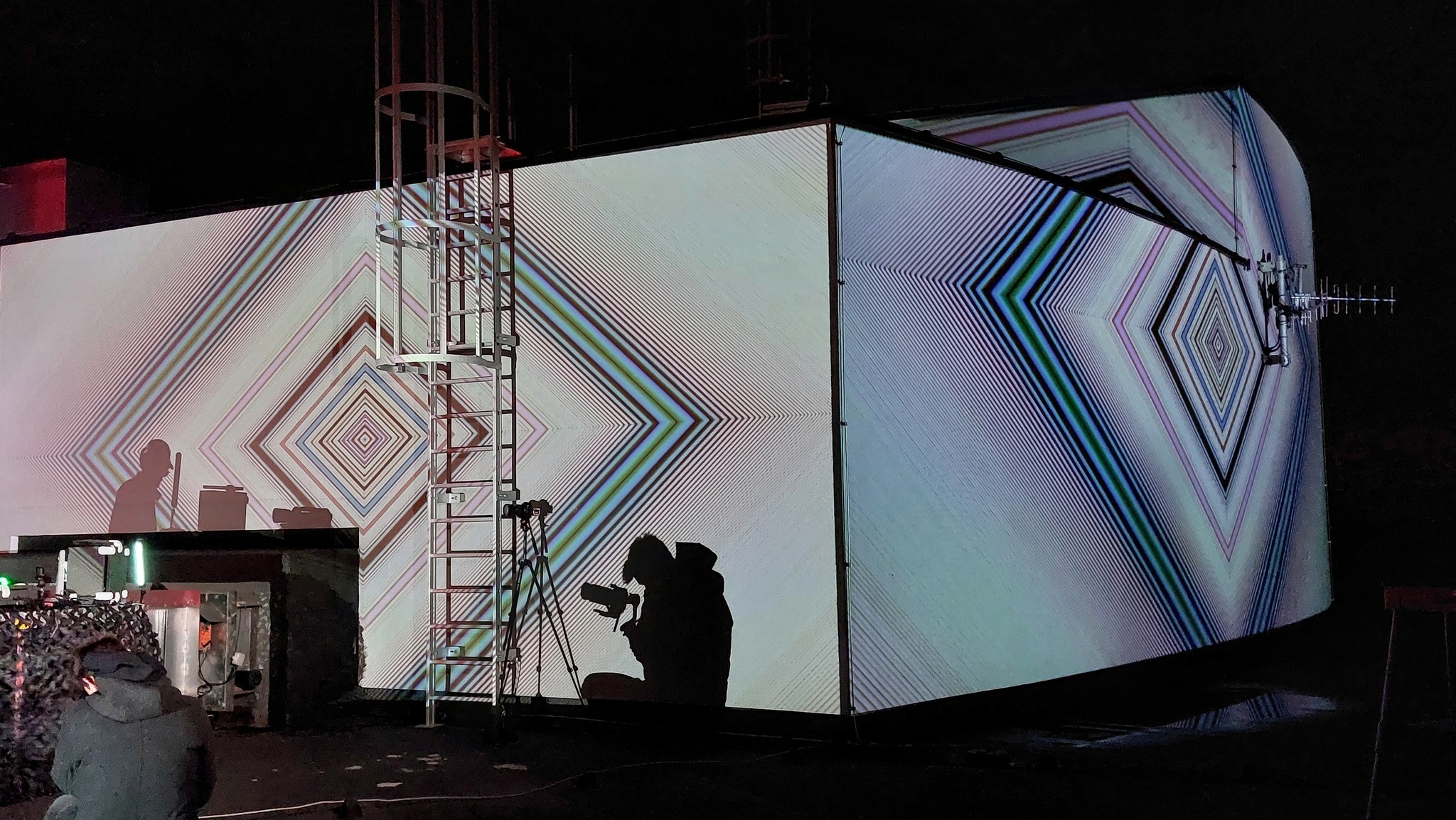 Light projection on a wall with the shadow of a Videographer