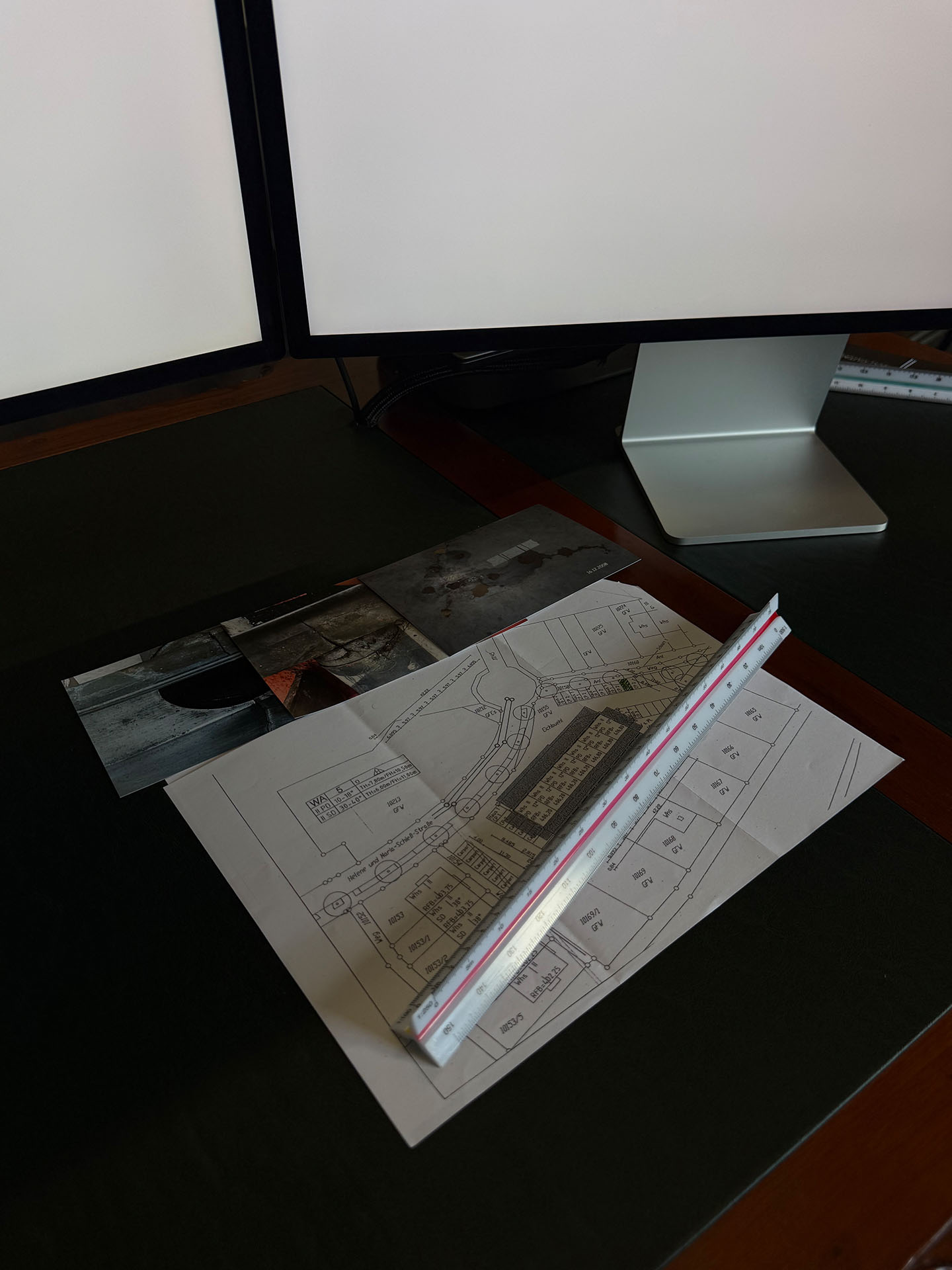 Lageplan und Detailfotos einer Immobilie auf dem Schreibtisch eines Gutachters