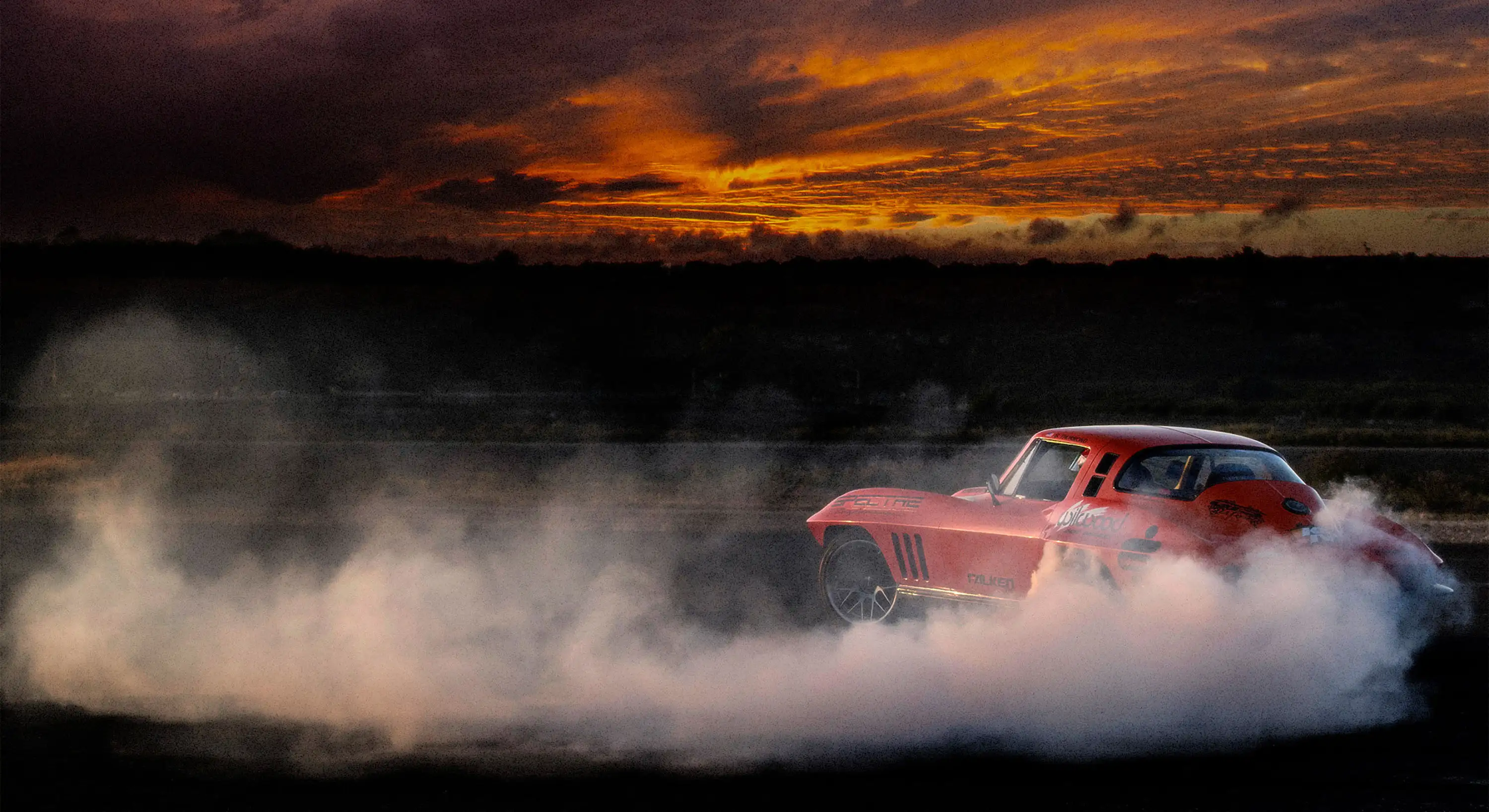 A red sports car doing a burnout