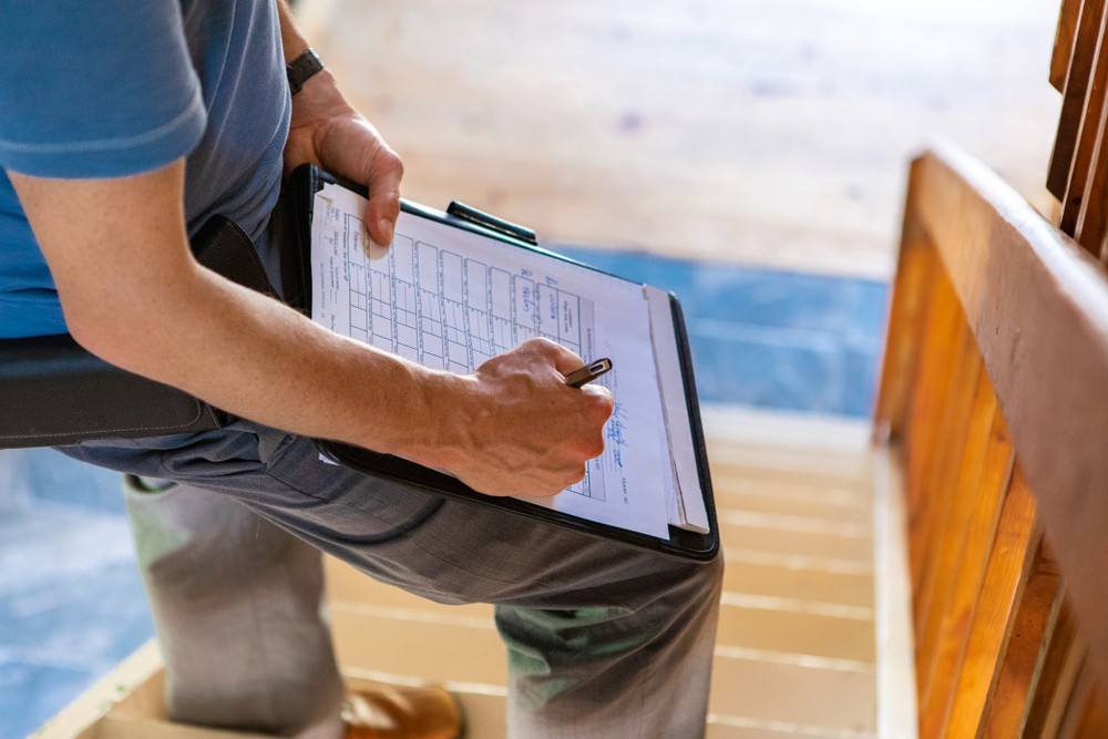 Home inspector filling out an inspection checklist on a clipboard at a job site
