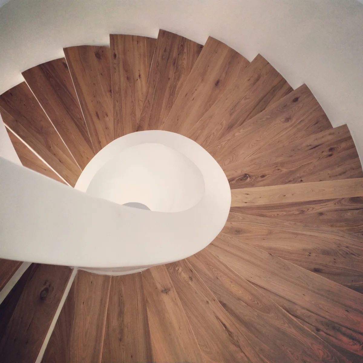 Escalier en colimaçon vu du dessus, marches en bois de chêne et limon blanc sculpté, rénovation intérieure sur mesure en Île-de-France