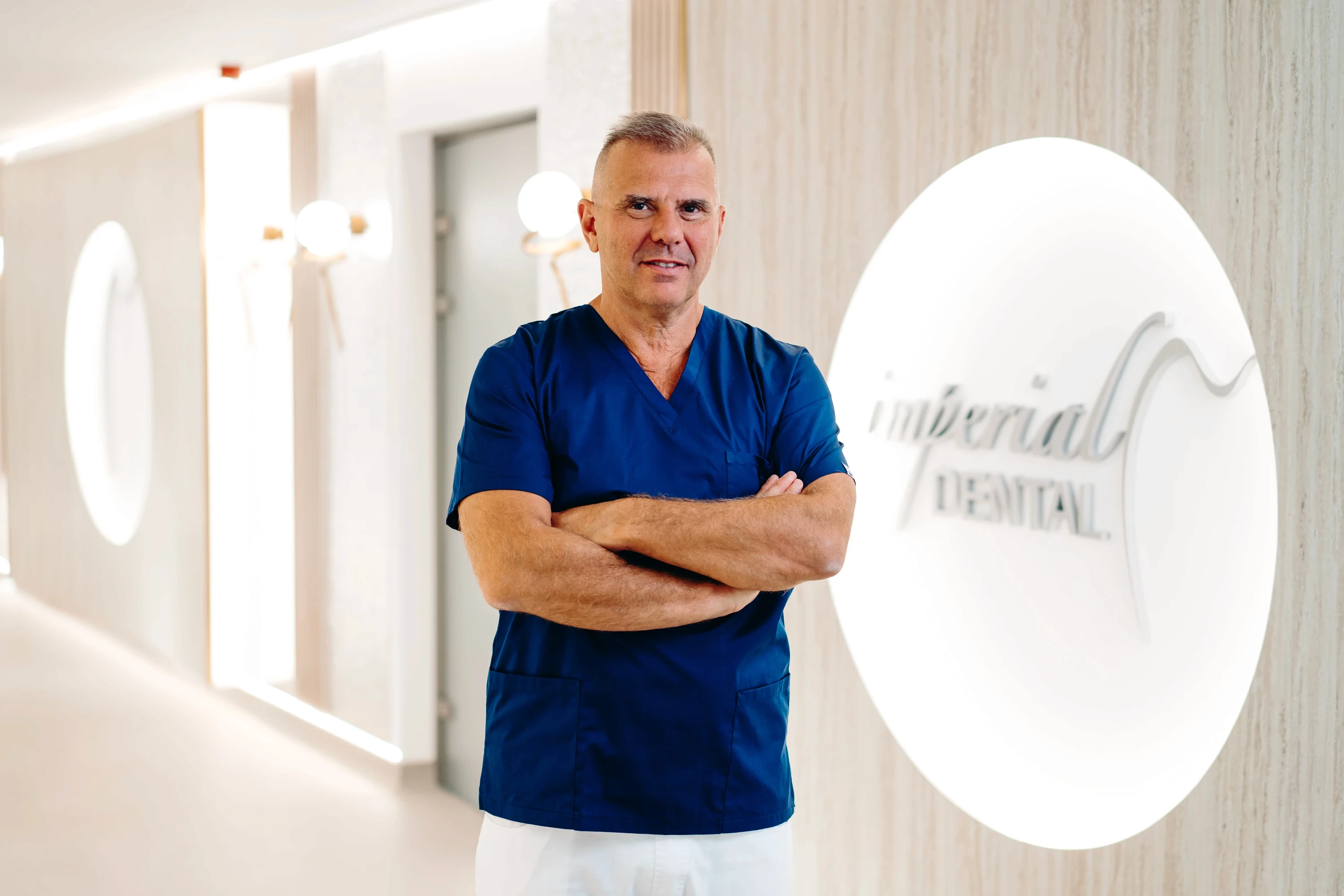 Az Imperial Dental vezető orvosa, a klinika folyosólyán sötét kék orvosi öltözékben.