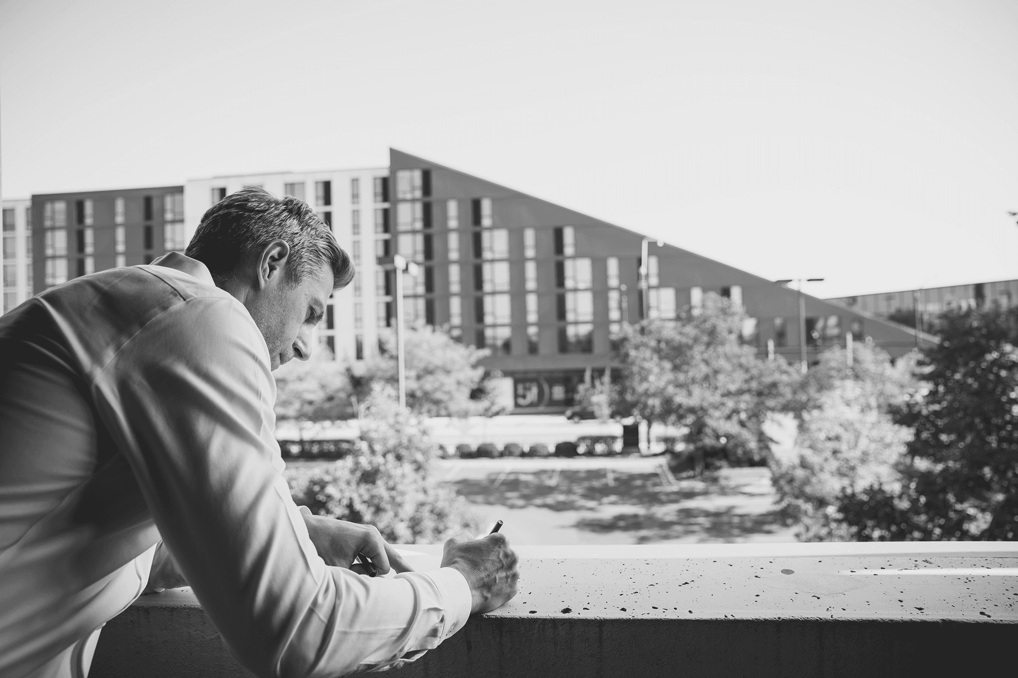 Close-up portrait of a person wearing a gray insulated hooded jacket with the hood up, showing their face framed by the hood against a light background.