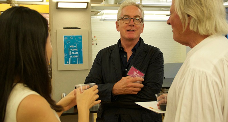 A photo of three people talking in an office room.
