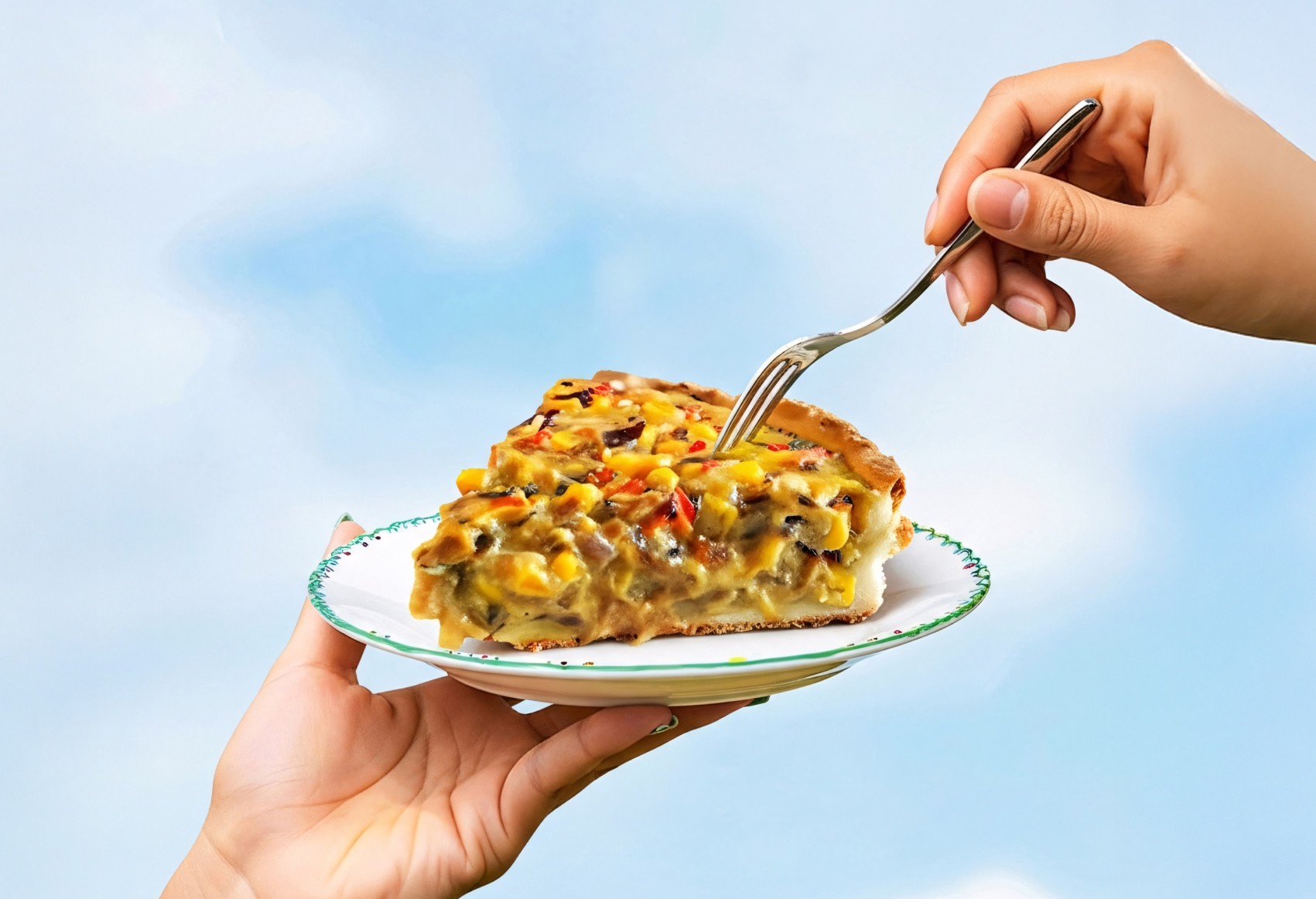 A slice of savory vegetable quiche, rich in bright yellow corn and zucchini, is held on a decorative white plate against a soft blue sky, while a fork is poised to take a bite.