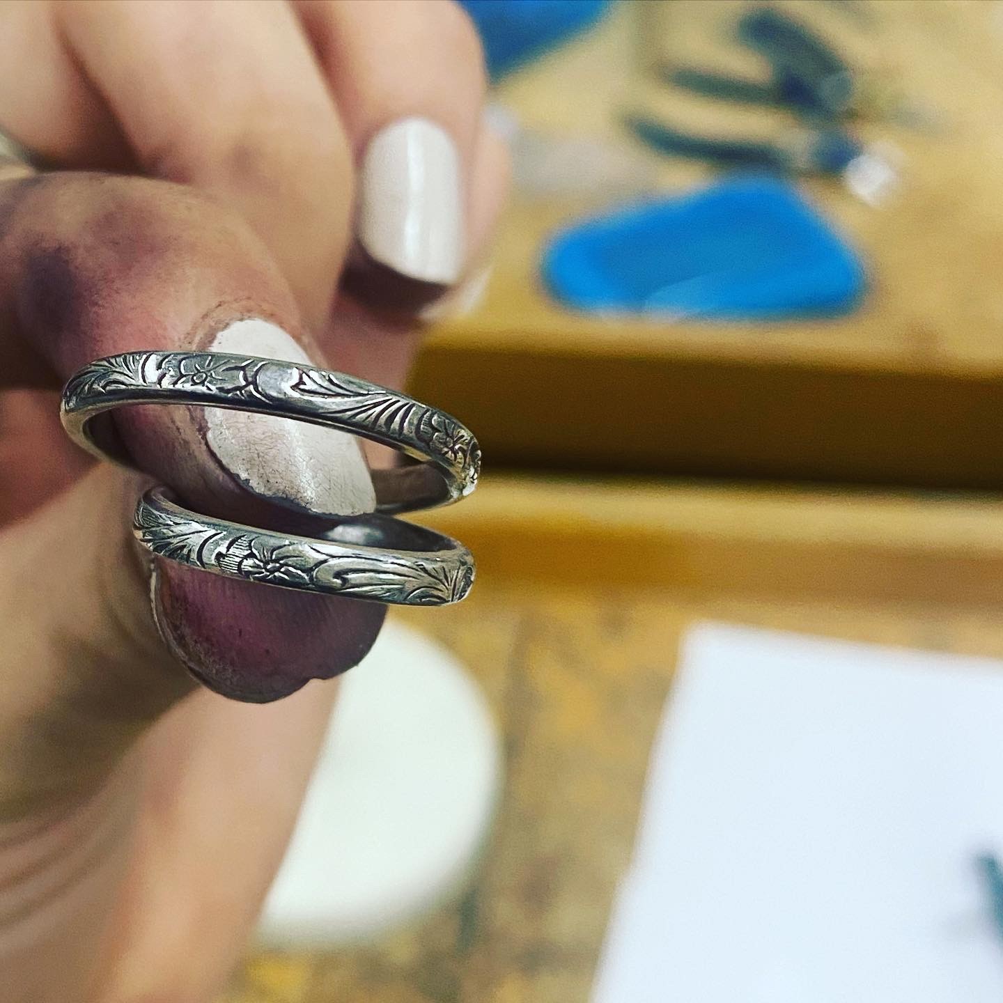 A view from an airplane window shows the aircraft's wing with a golden hue reflecting the setting sun, against a serene backdrop of fluffy clouds and a clear sky.