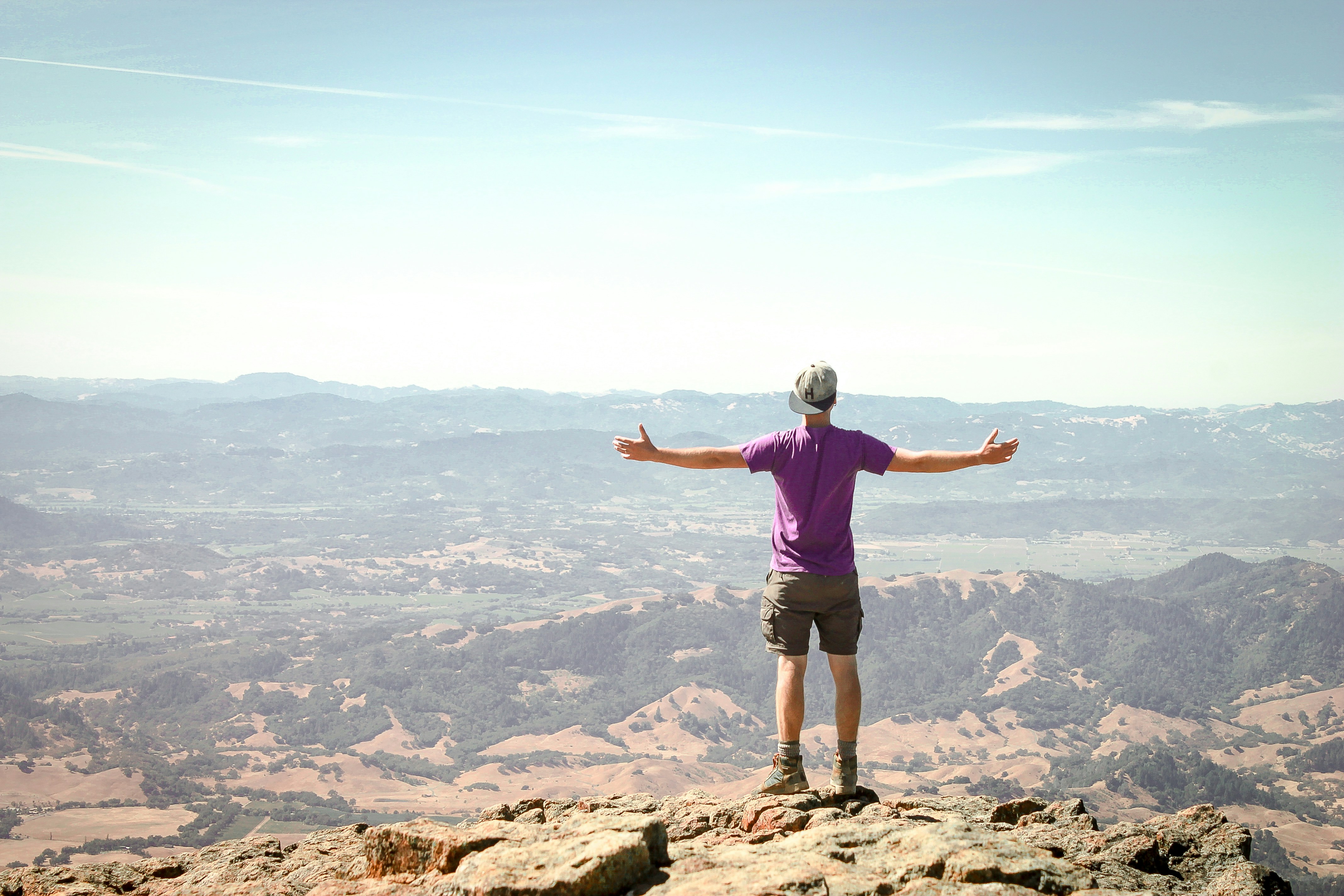 man stand on brown mountain under blue sky