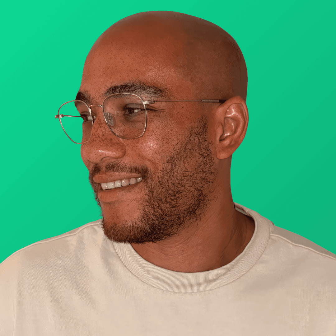 A smiling person with short, dark hair and a light-colored shirt against a dark background.