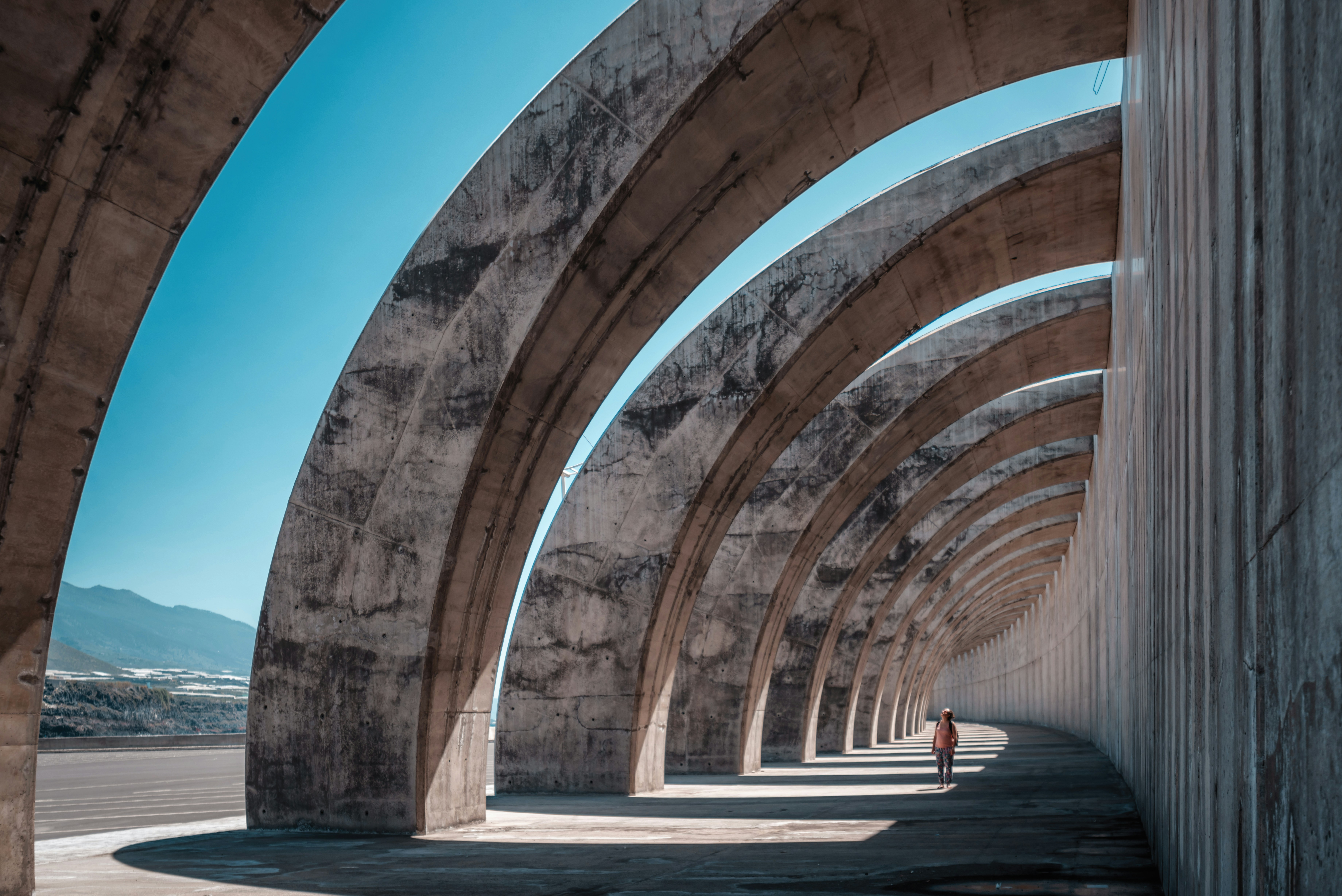 A person walking through large concrete arches, representing the structured pillars of AI SEO and the clear pathways needed to improve AI visibility and recover traffic lost to AI.
