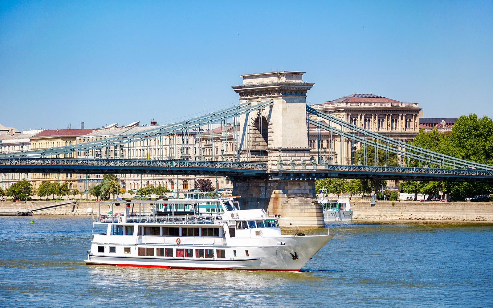Kreuzfahrtschiff auf der Donau, das unter der Kettenbrücke in Budapest hindurchfährt.