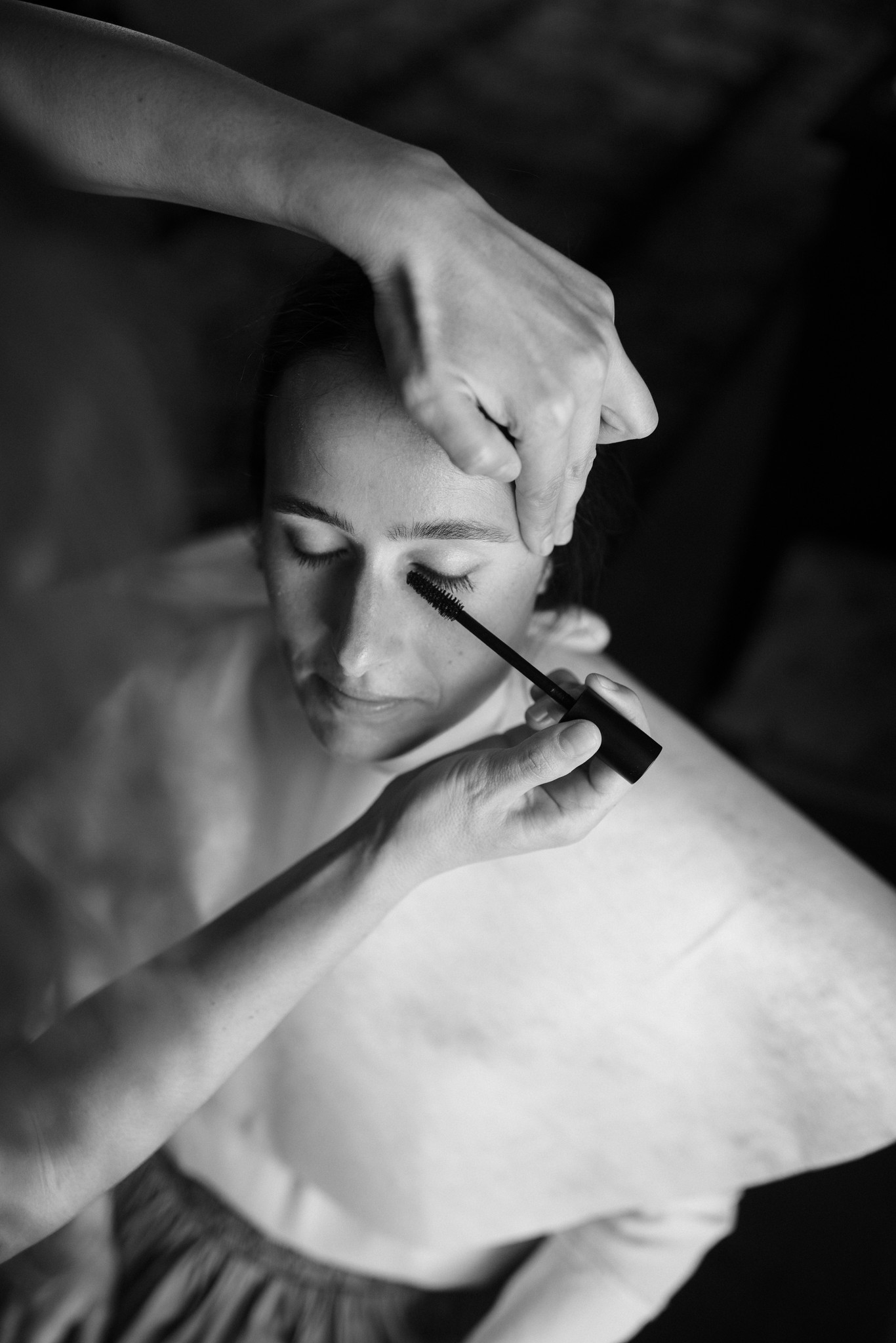 Sposa trucco occhi durante i preparativi matrimoniali, ritratto in bianco e nero con pennello applicativo