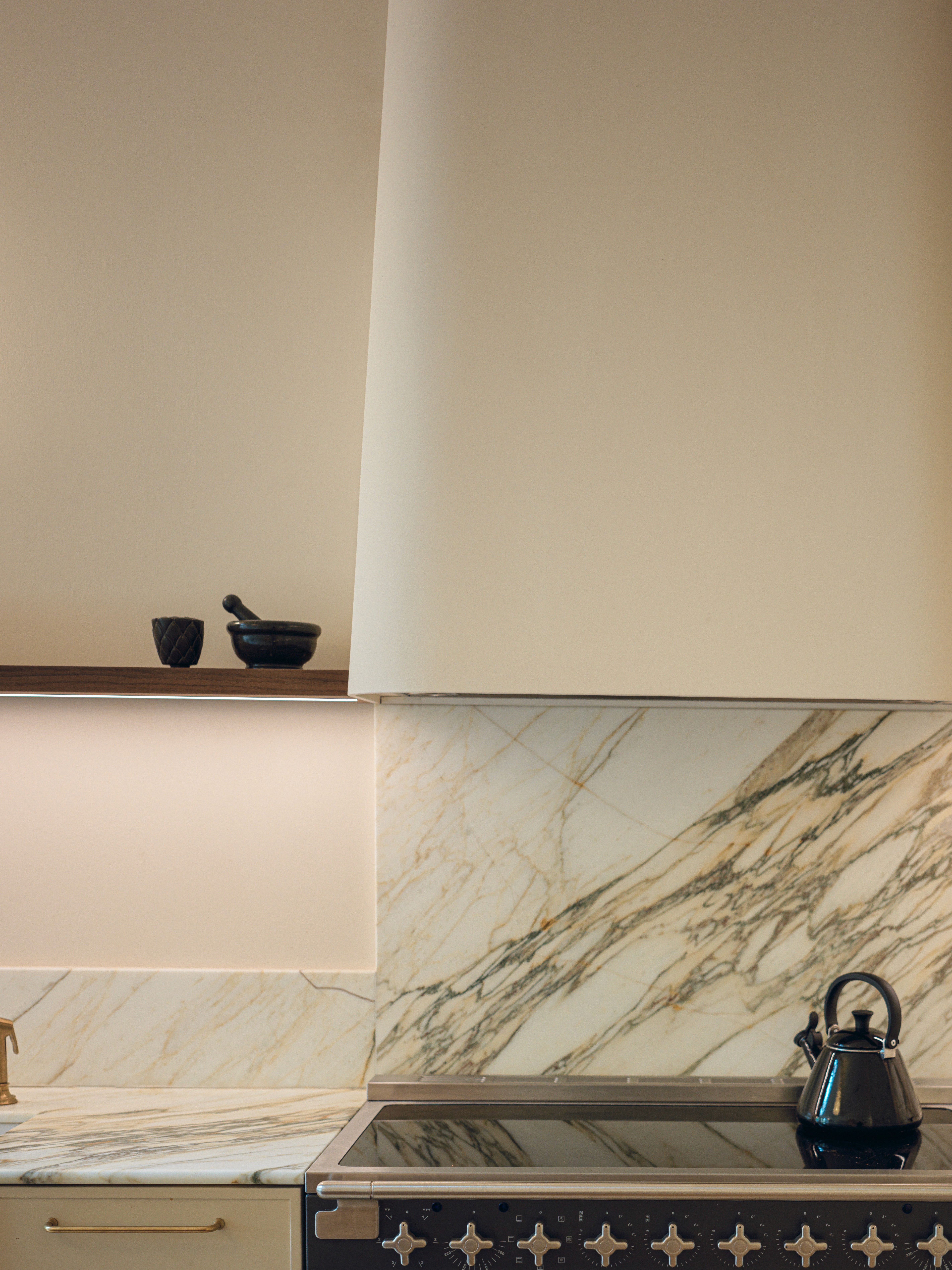 Minimal stone splashback detail with soft neutral cabinetry and open shelving