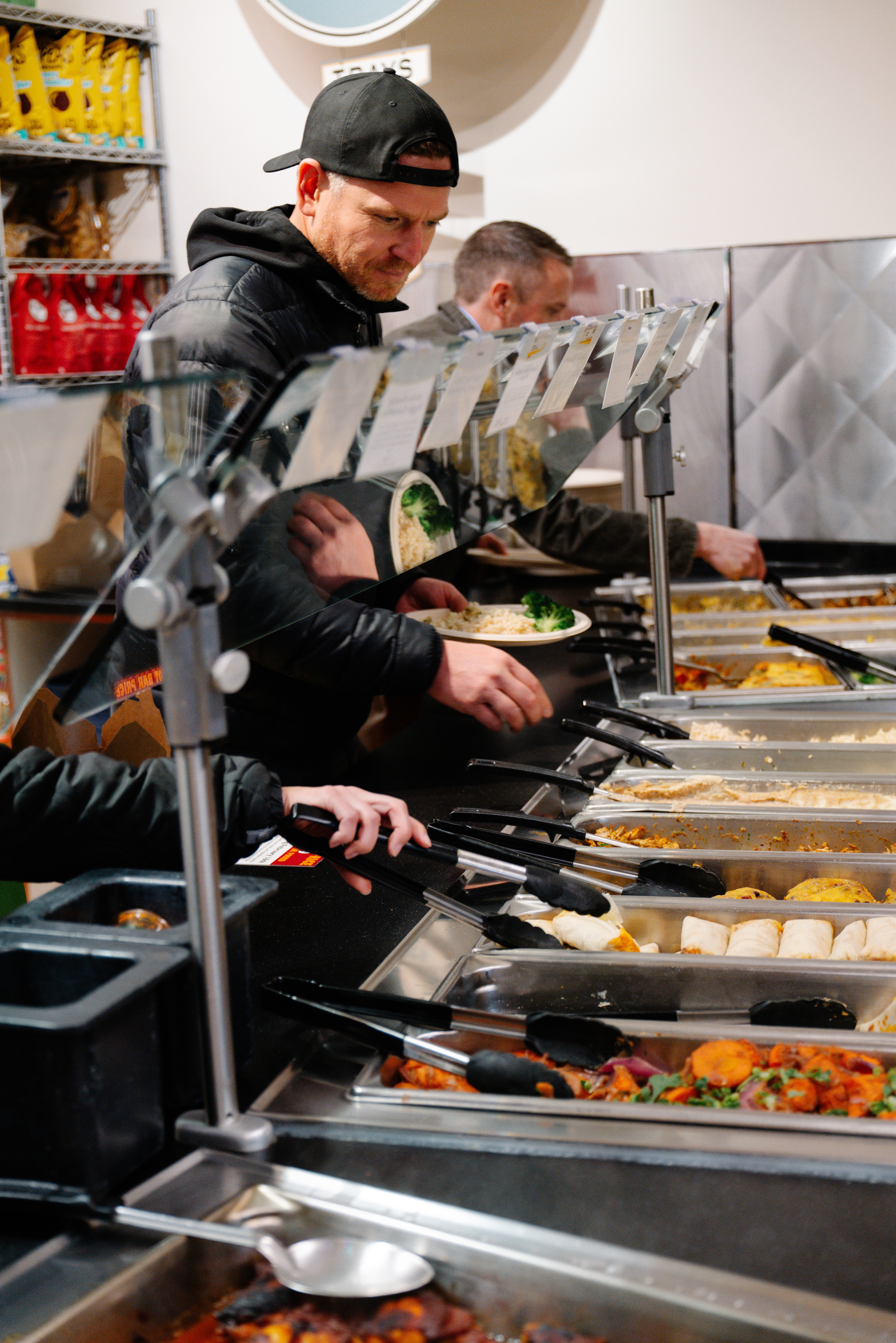 A chef stirs a pot over a high flame in a busy kitchen, showcasing vibrant fire and intense cooking.