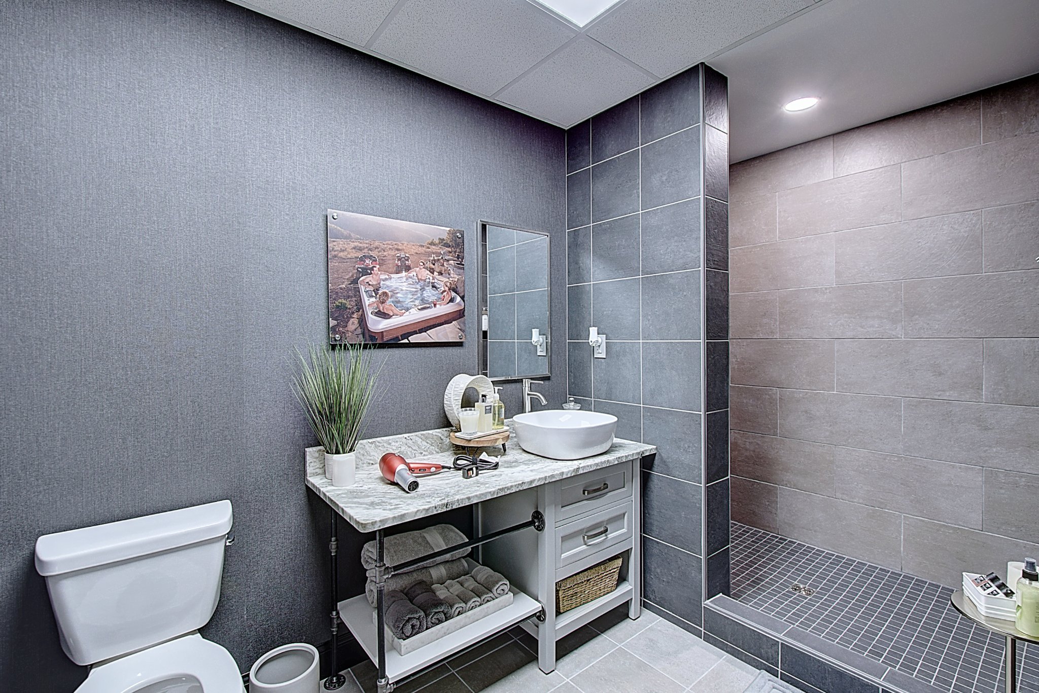 Modern bathroom featuring a toilet, vanity with decor, and a walk-in shower with neutral-colored walls.