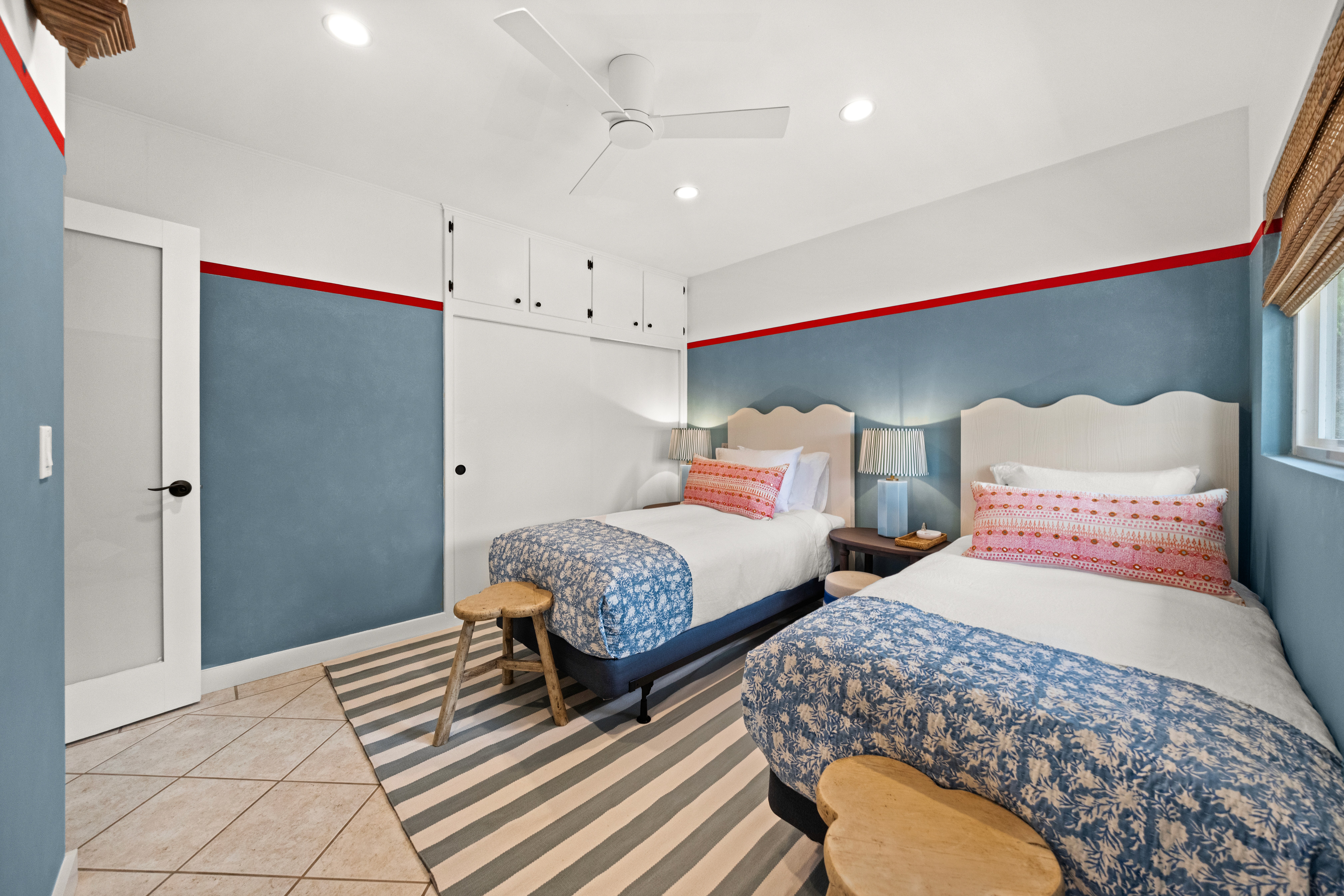 Playful twin bedroom with custom painted walls, striped rugs, and cheerful bedding—perfect for families or friends.
