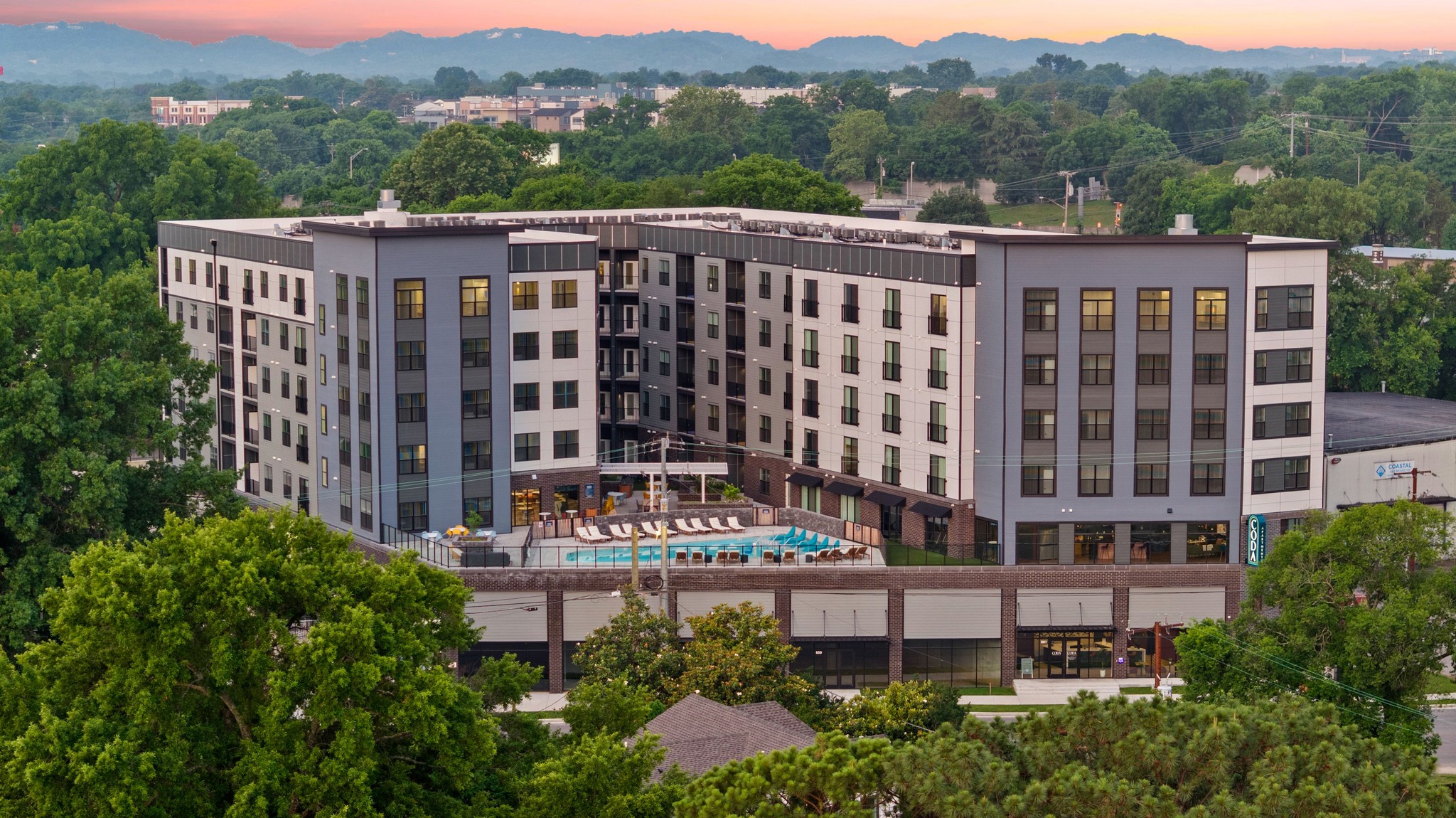 A scenic hotel nestled in the mountains, surrounded by lush greenery and towering peaks.
