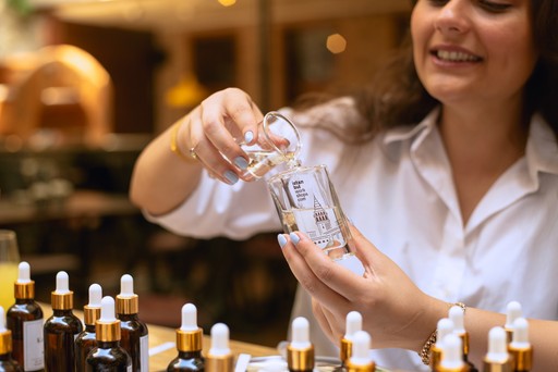 A participant in a perfume workshop holding a bottle while adding a selected scent, highlighting the hands-on experience of crafting a custom fragrance in Istanbul.