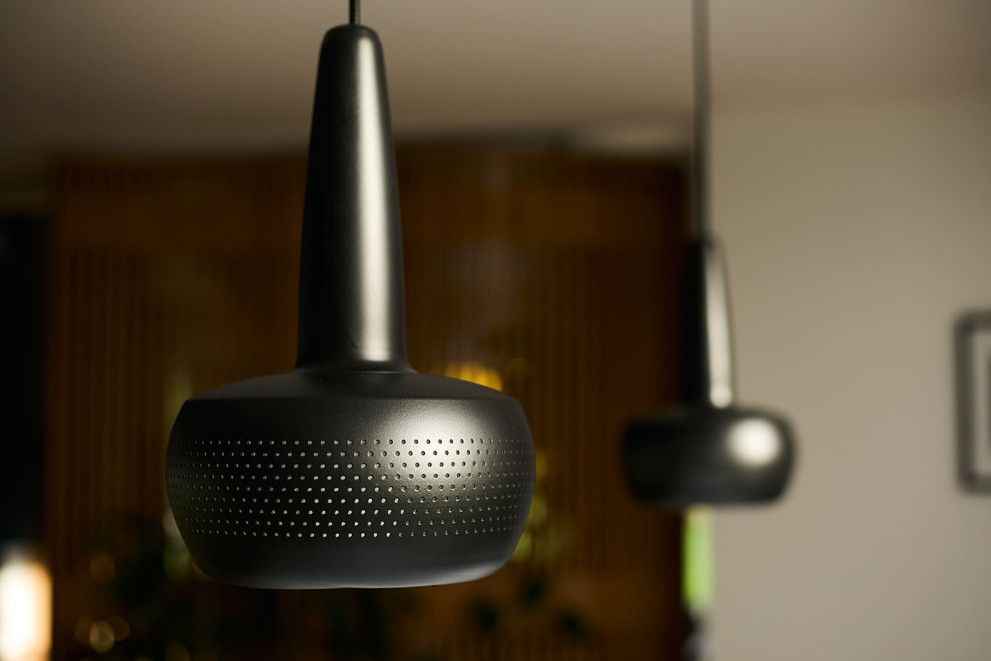 Gros plan sur deux luminaires noir qui surplombe un billard.