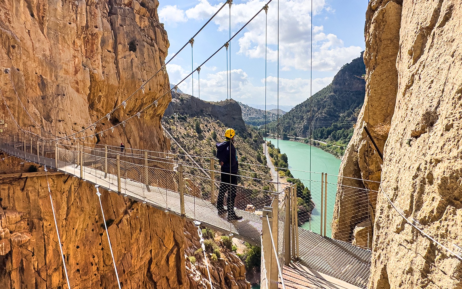 Caminito del Rey walkway with hiker overlooking river gorge in Spain.
