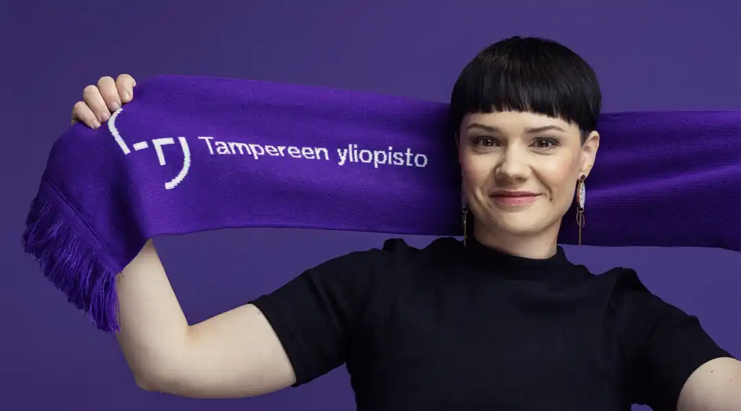 A woman holding a purple scarf with the word tempersyj, representing Tampere University