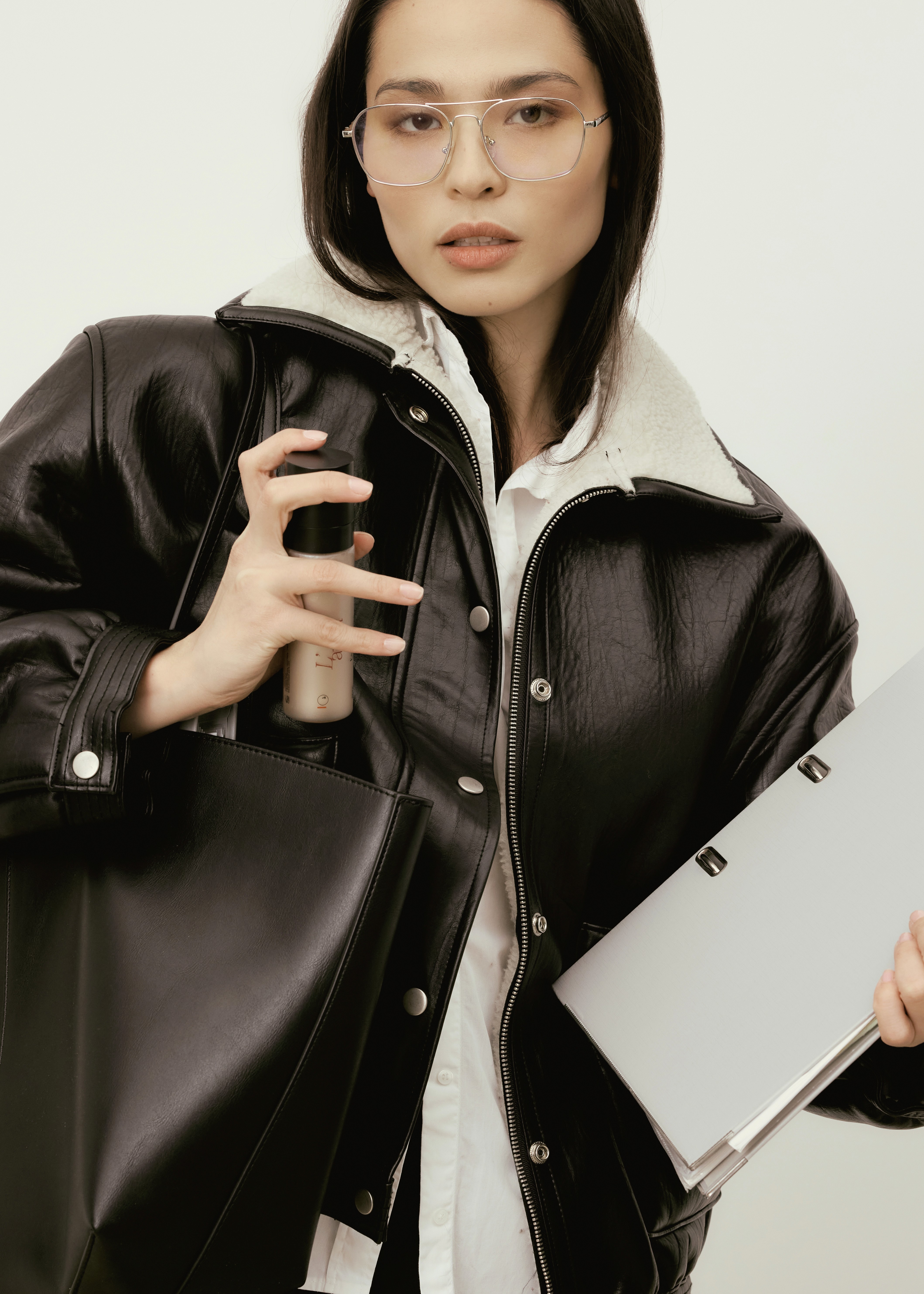 portrait femme habillée d'un blouson en cuir tenant un sac et des dossiers