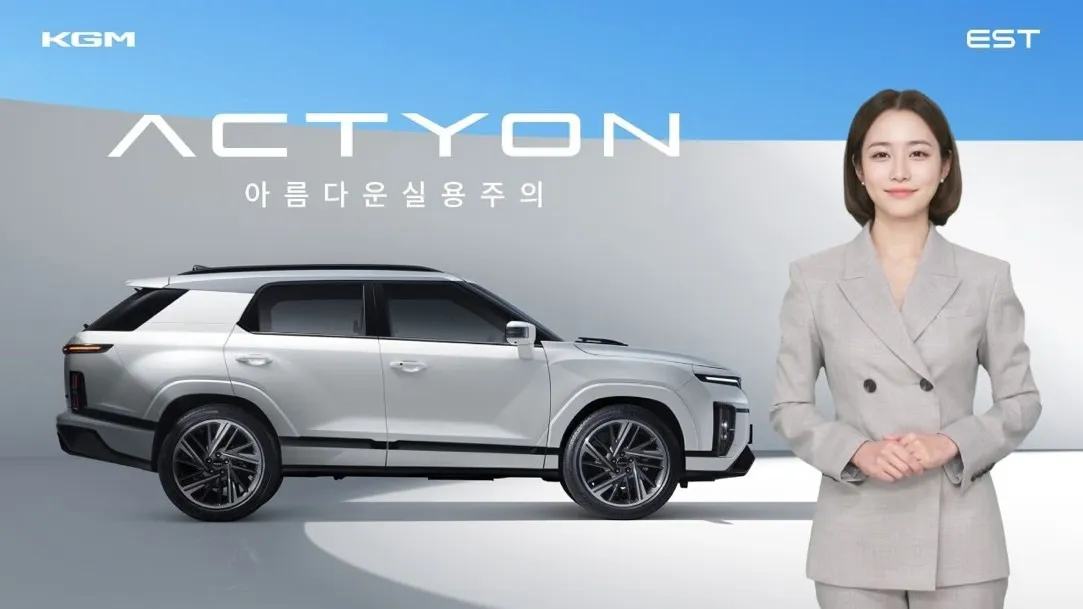 พรีเซนเตอร์ AI หญิงในชุดสูทสีเทายืนอยู่ข้างยานพาหนะแอคทีออนสีขาวแบรนด์ KGM ที่มีโลโก้ KGM และ ESTsoft