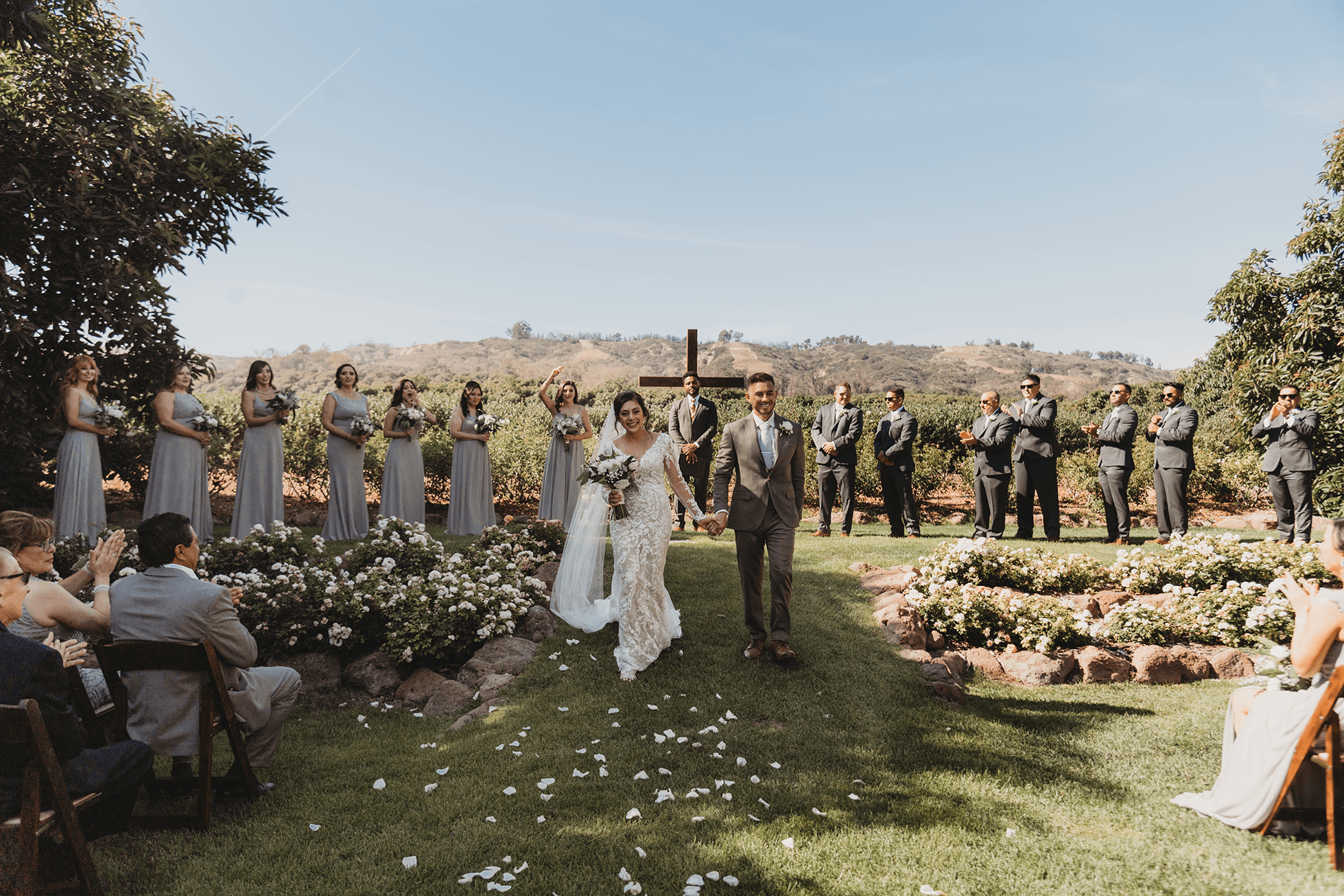 Bride and groom walking down the aisle with guests cheering