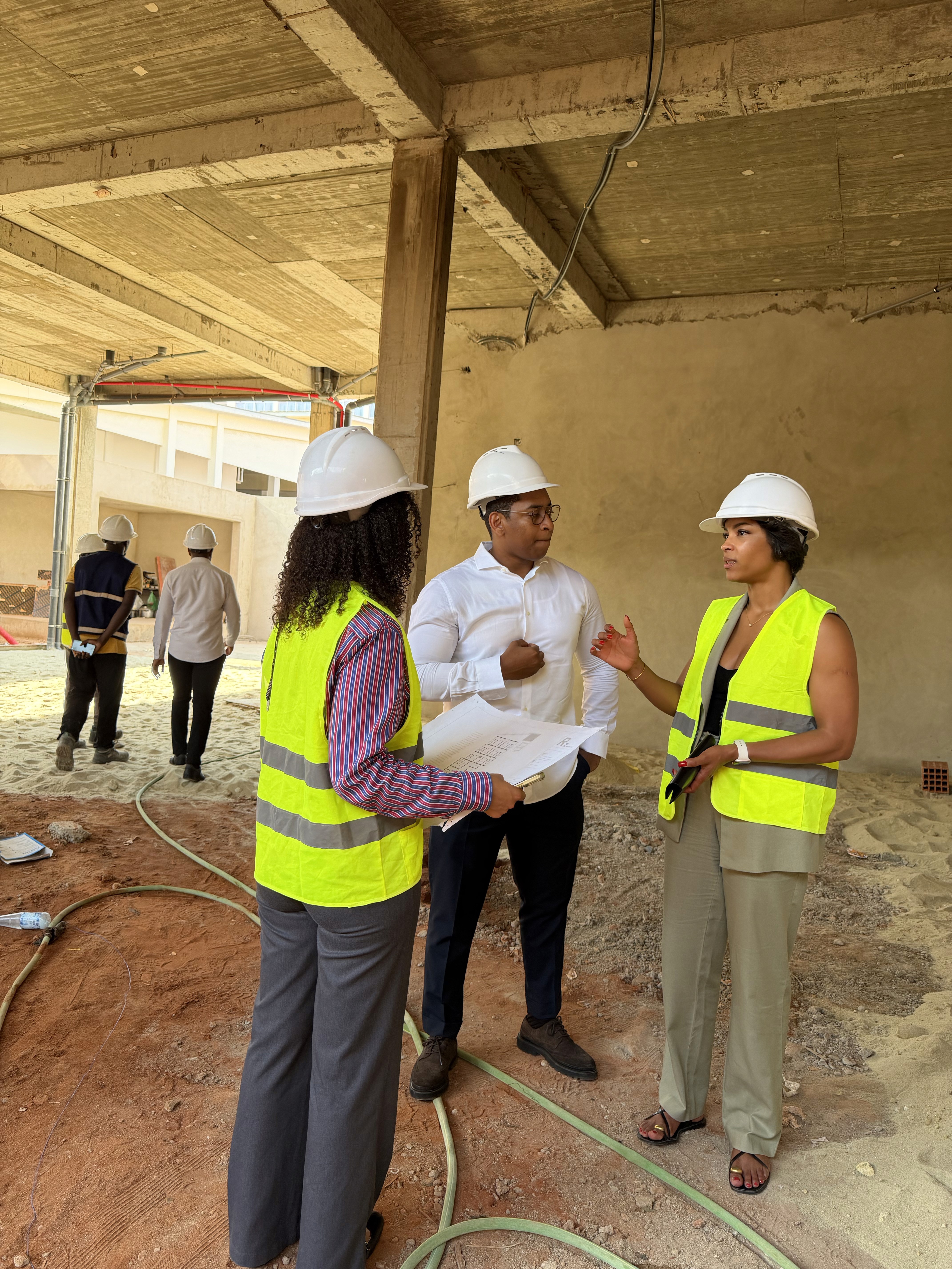 Construction workers in red helmets and safety vests work on tall rebar structures against a blue sky, conveying teamwork and industriousness.